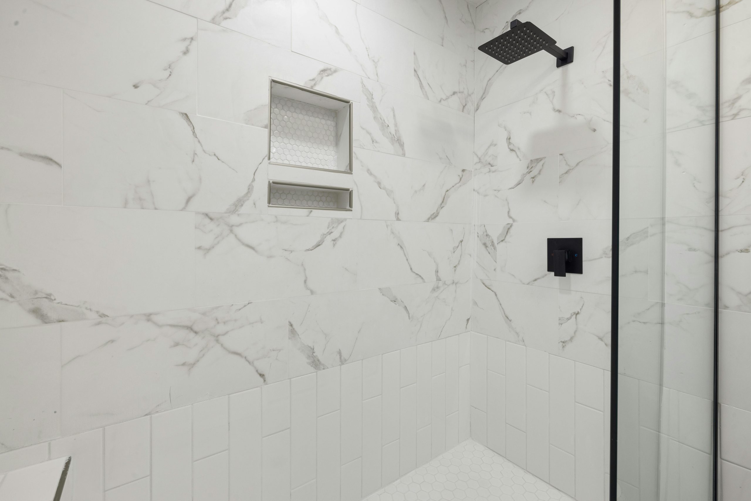 Sleek bathroom shower featuring marble tiles and black fixtures, perfect for modern luxury home design.