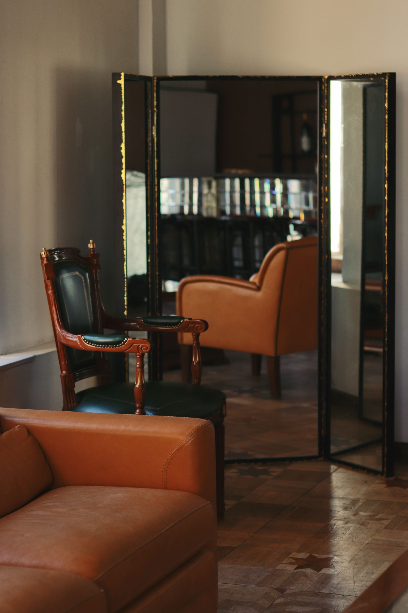 Sophisticated living room featuring elegant armchair and large mirror reflection for a classic touch.