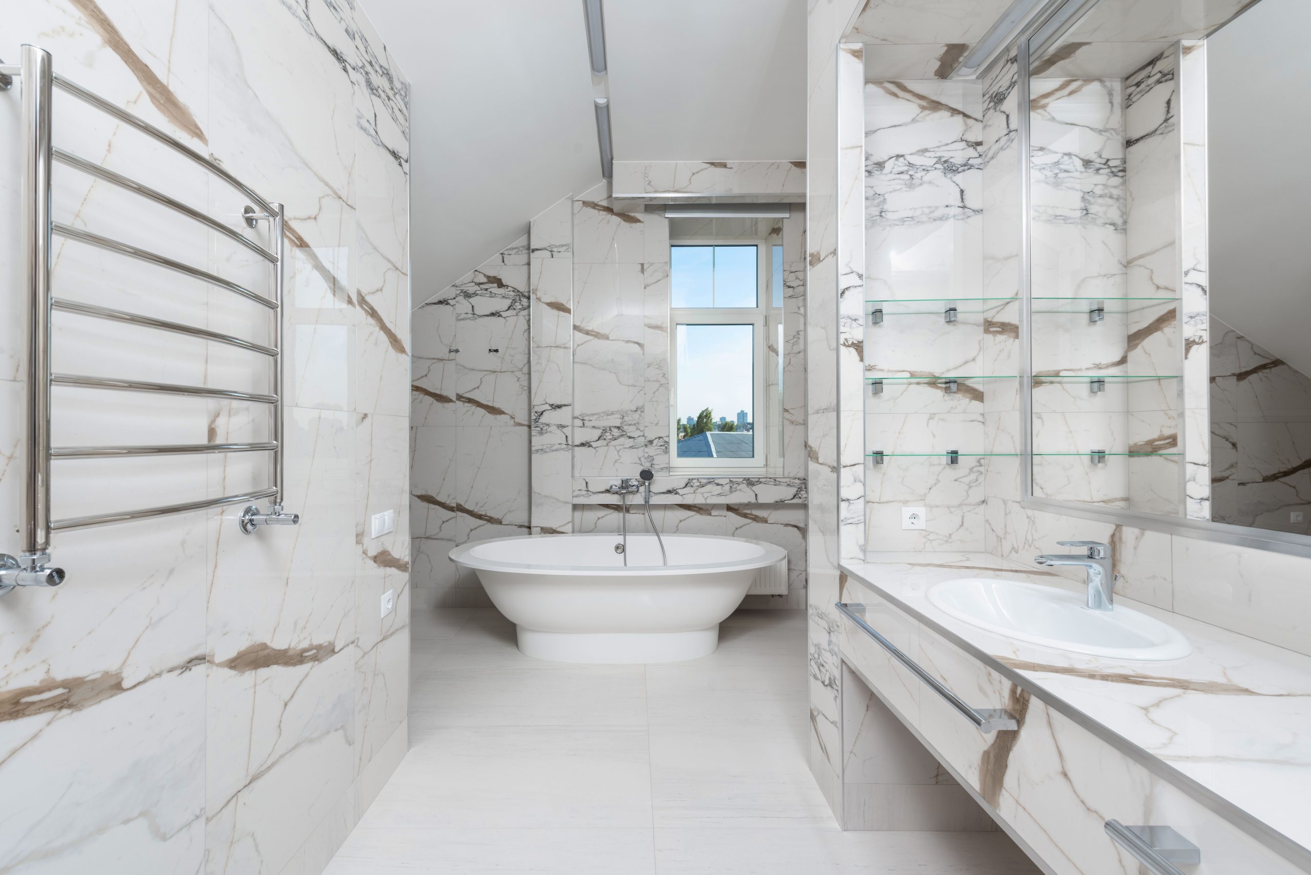 Spacious and elegant marble bathroom featuring a modern bathtub, sink, and glass window.