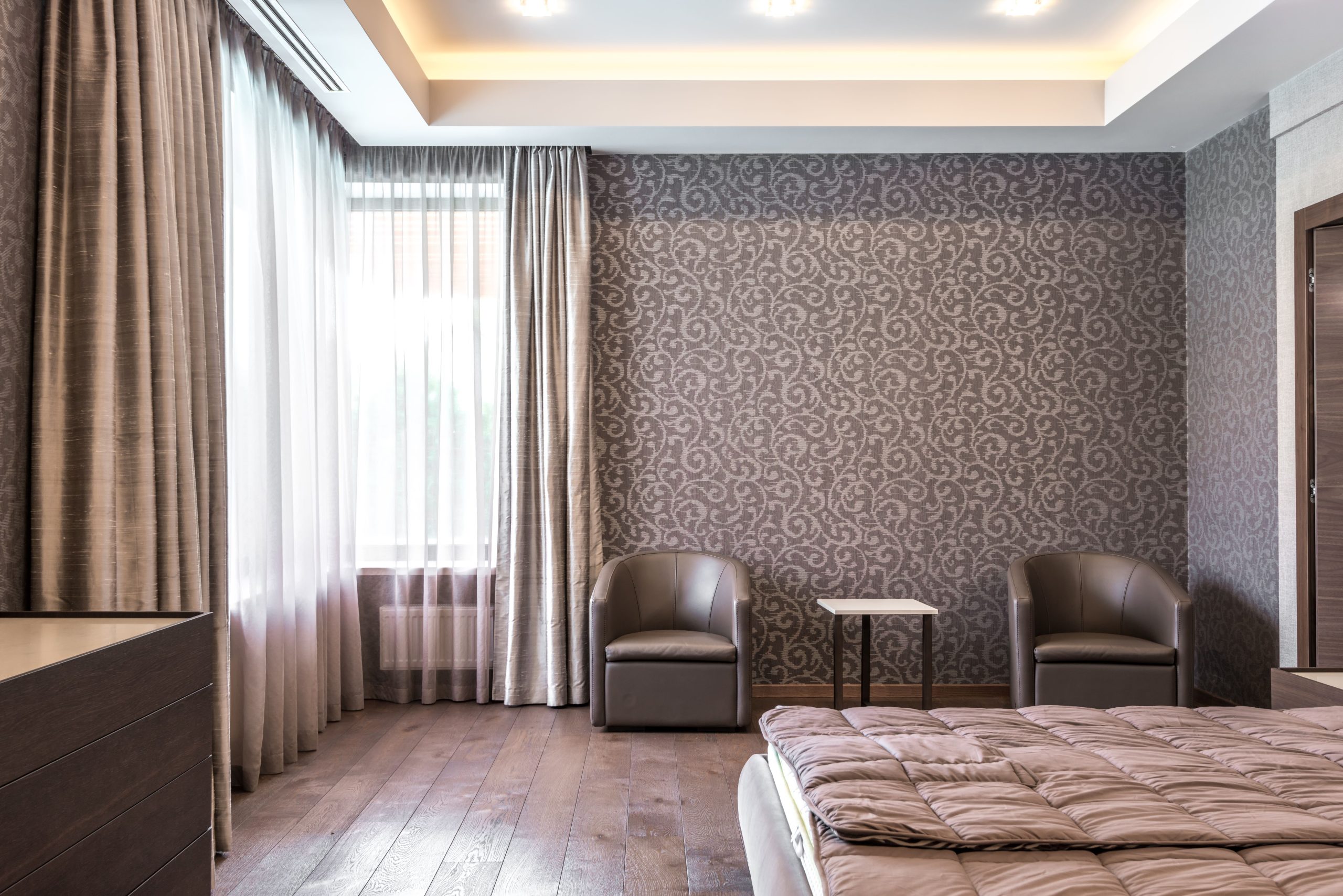 Spacious modern bedroom with stylish wallpaper and elegant furnishings.