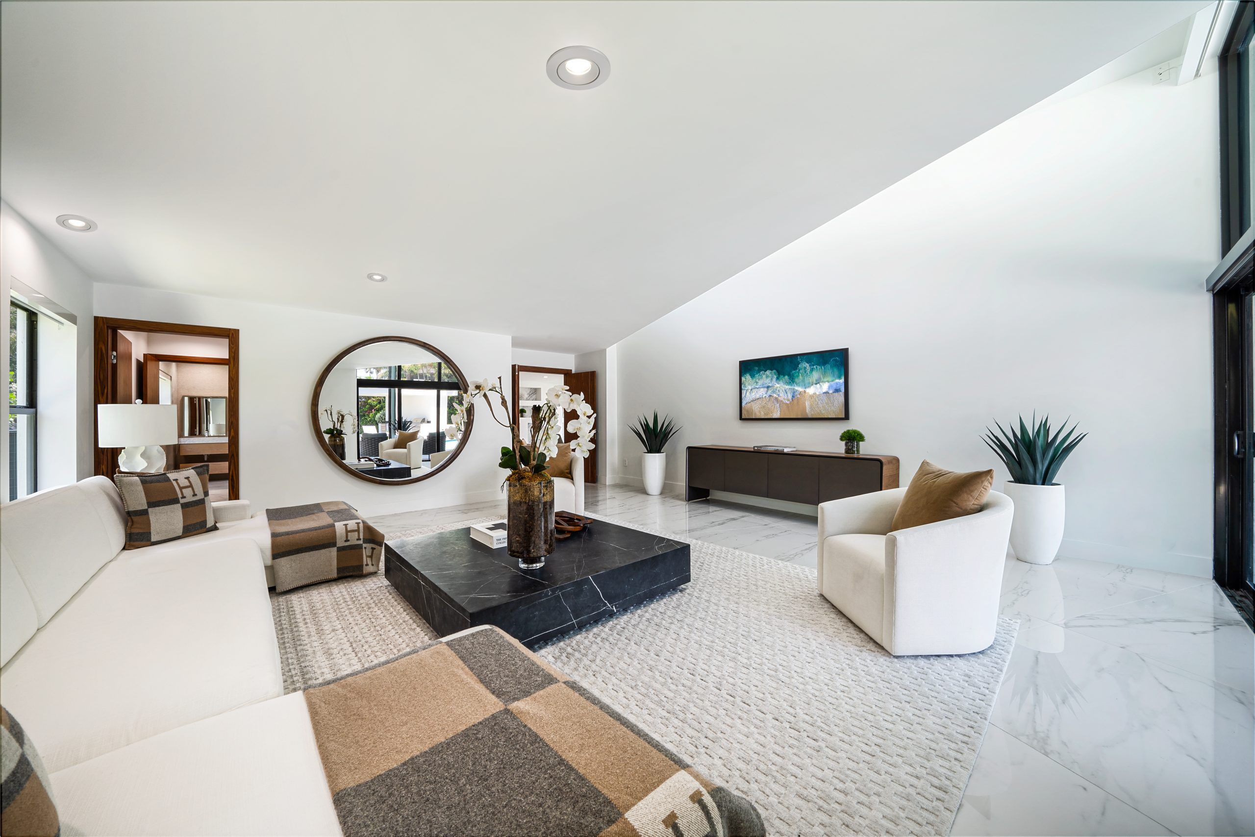 Spacious modern living room with neutral decor, large mirror, and elegant furnishings.