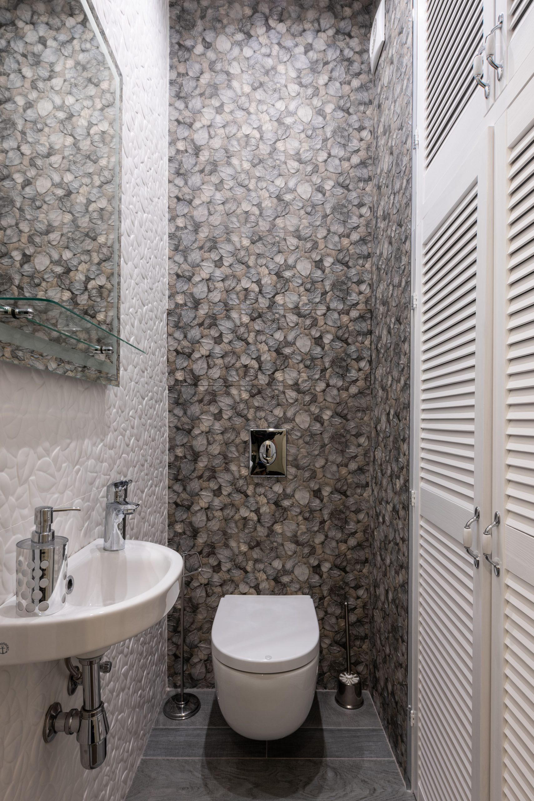 Stylish and compact bathroom featuring modern fixtures, elegant tiles, and a minimalist sink and toilet setup.