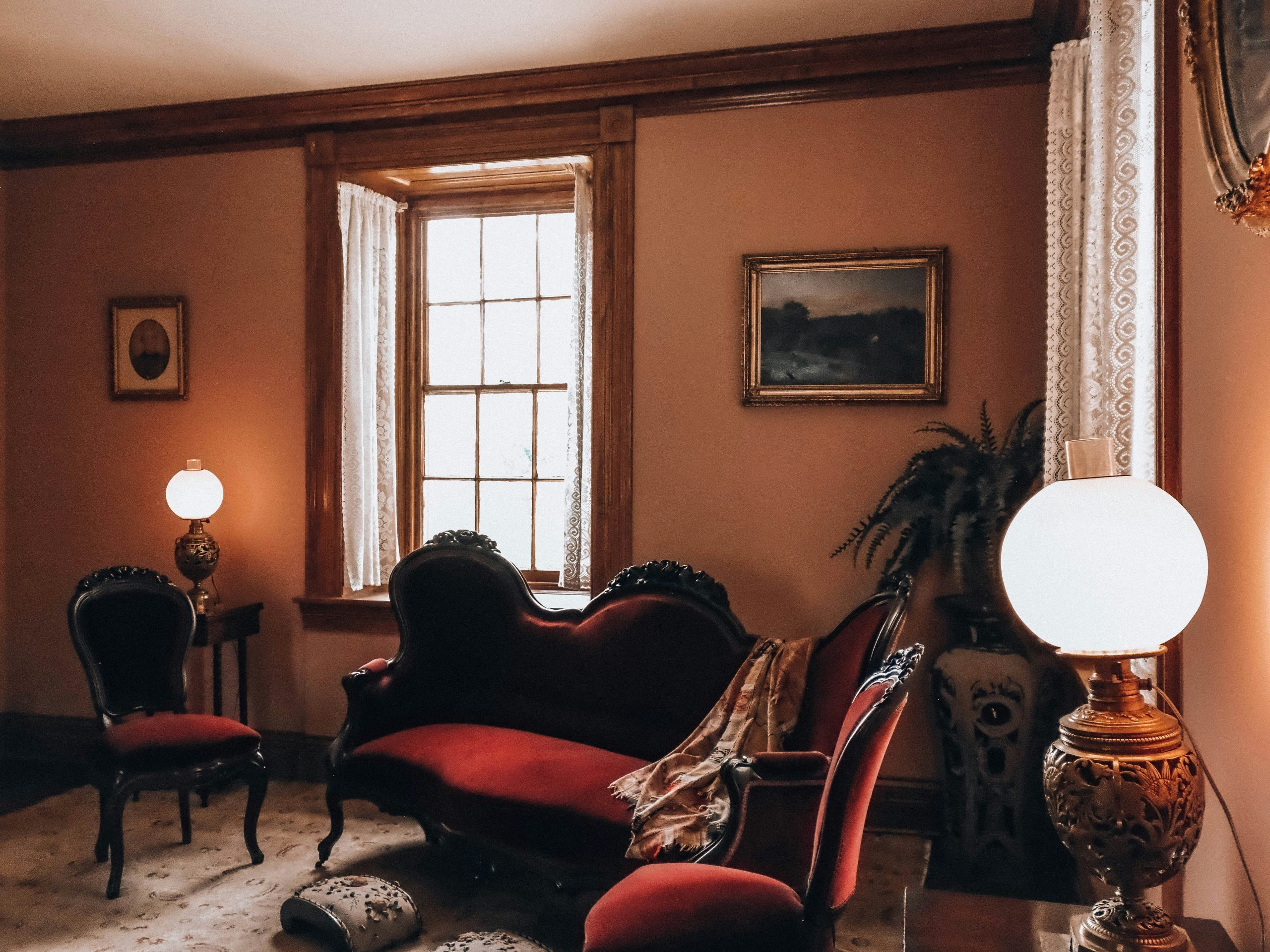 Vintage living room with red velvet sofa and antique lamps.