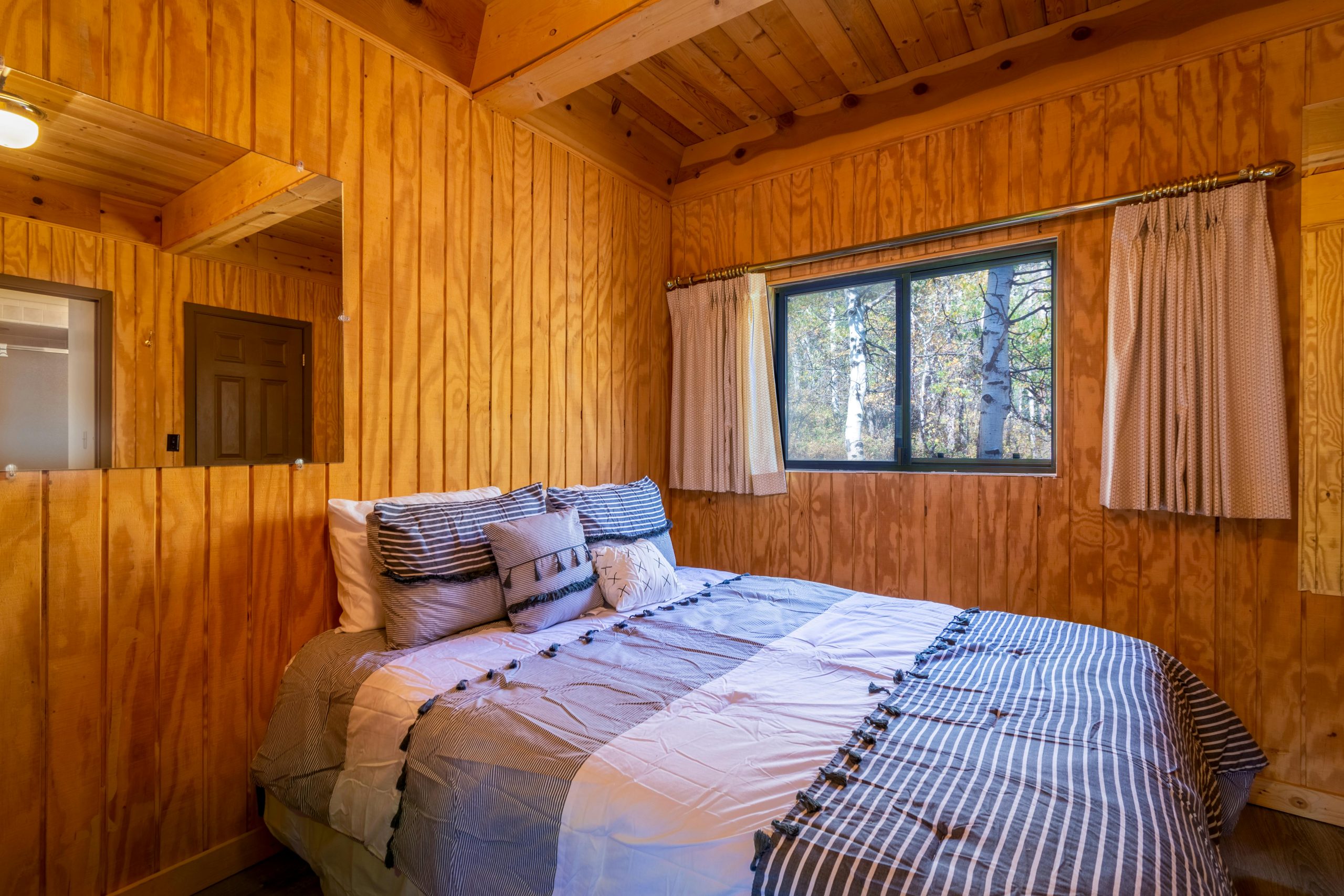 Warm and inviting wooden cabin bedroom with a comfortable bed and window view.