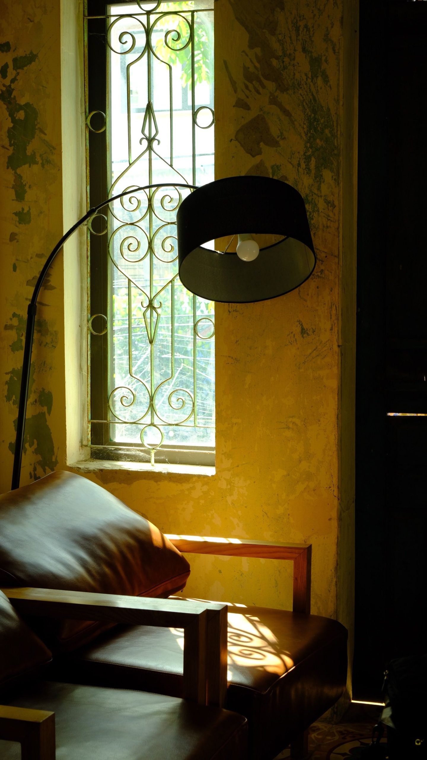 Warm vintage interior with a leather armchair, lamp, and window casting natural light.