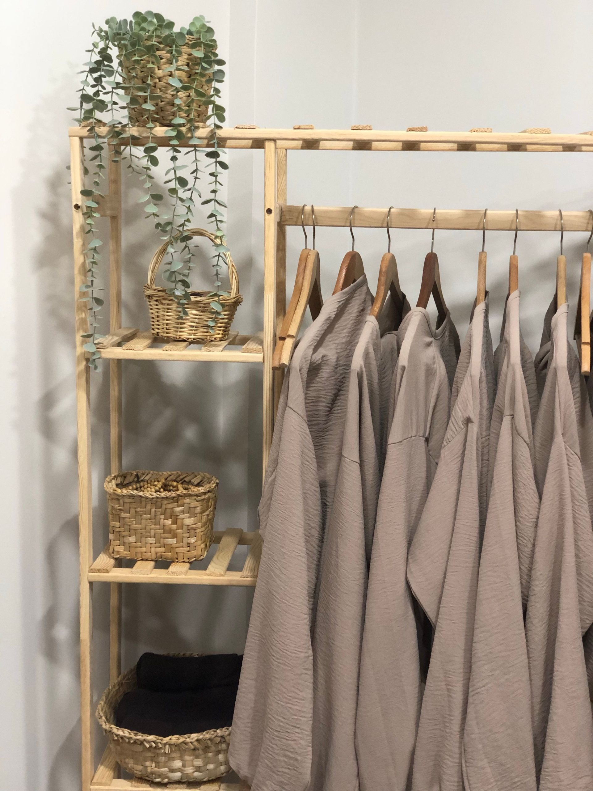Wooden rack with linen clothes and woven baskets, minimalist decor.