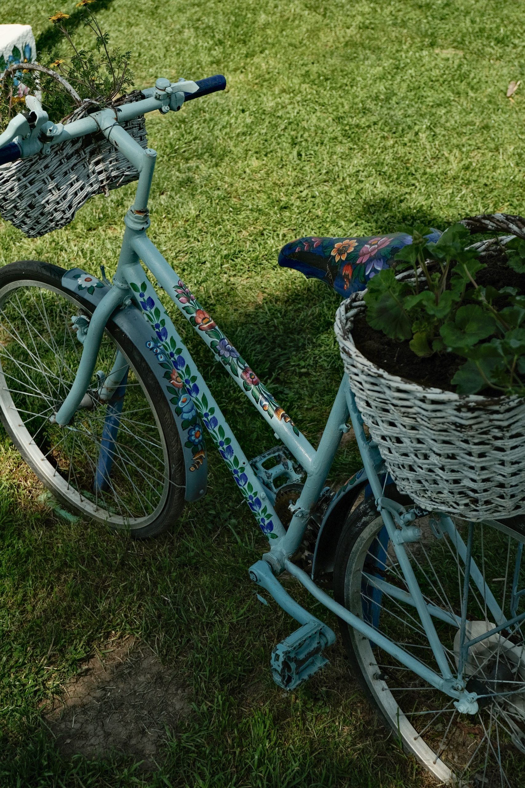 A charming vintage bicycle adorned with floral patterns and baskets on a sunny day outdoors.