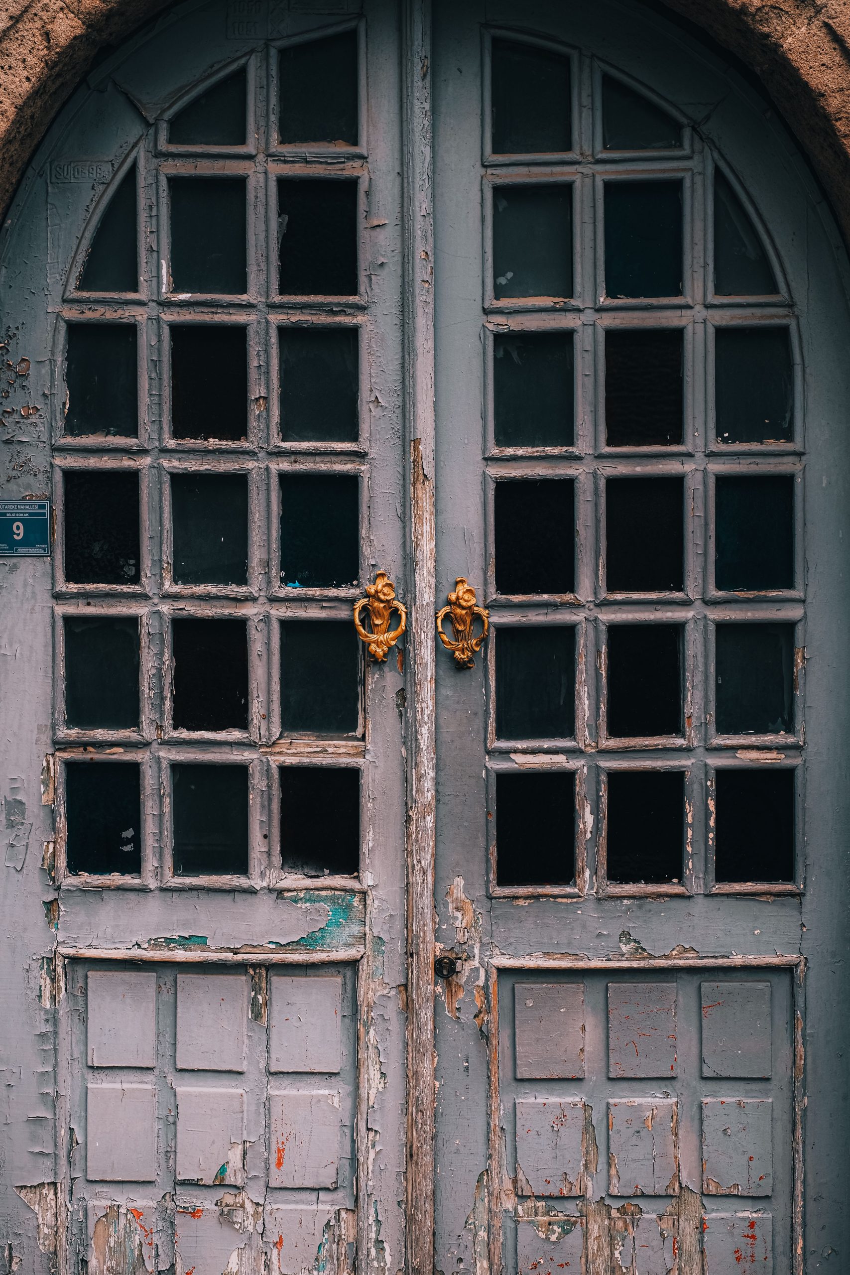 A close-up view of a weathered vintage wooden door with peeling paint and ornate handles.