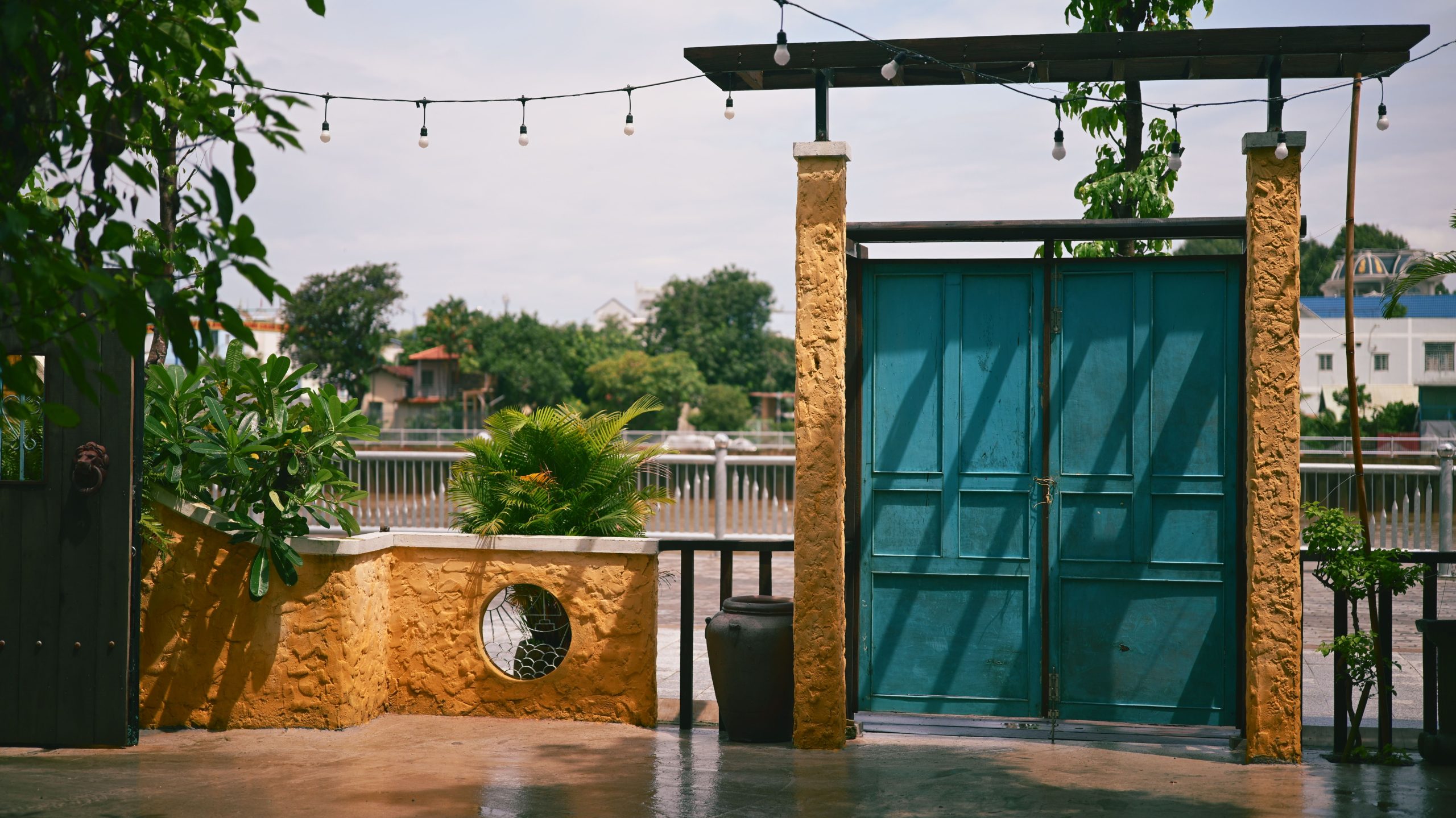 A cozy outdoor patio with turquoise doors, vibrant plants, and a rustic vibe, perfect for relaxation.