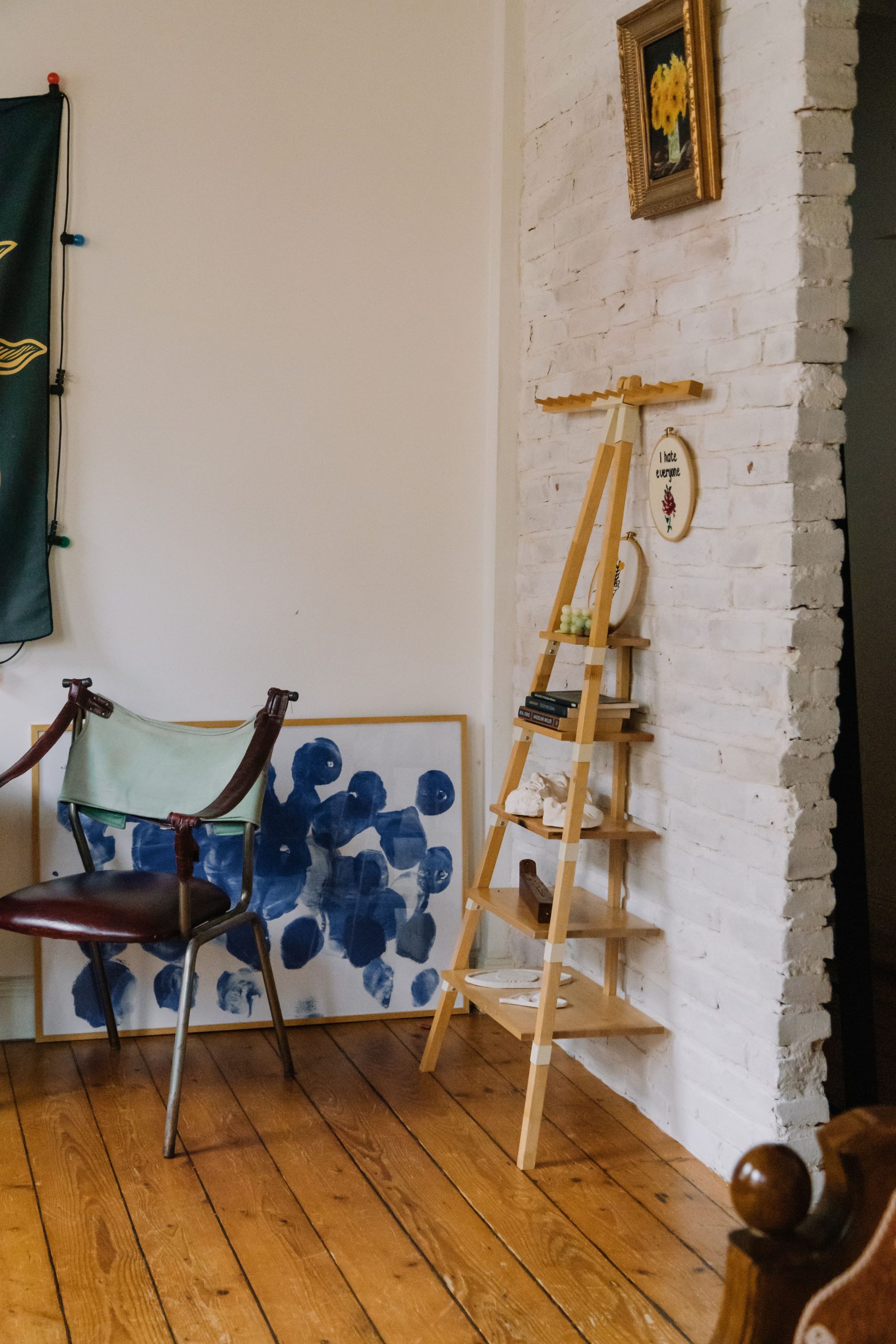 A cozy room corner featuring art, a chair, and unique shelving displaying decor.