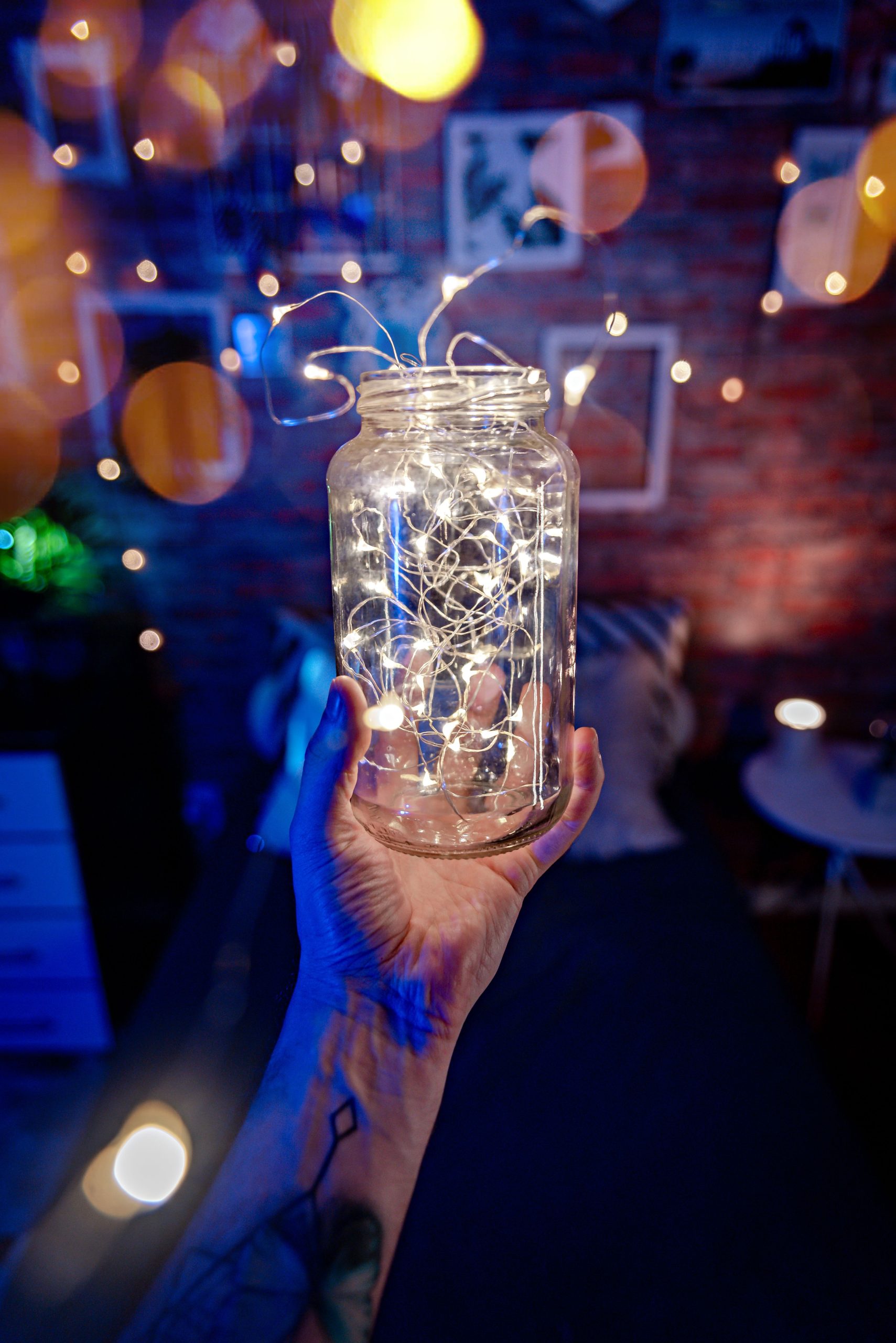 A hand holding a glass jar filled with glowing fairy lights, creating an ambient atmosphere.
