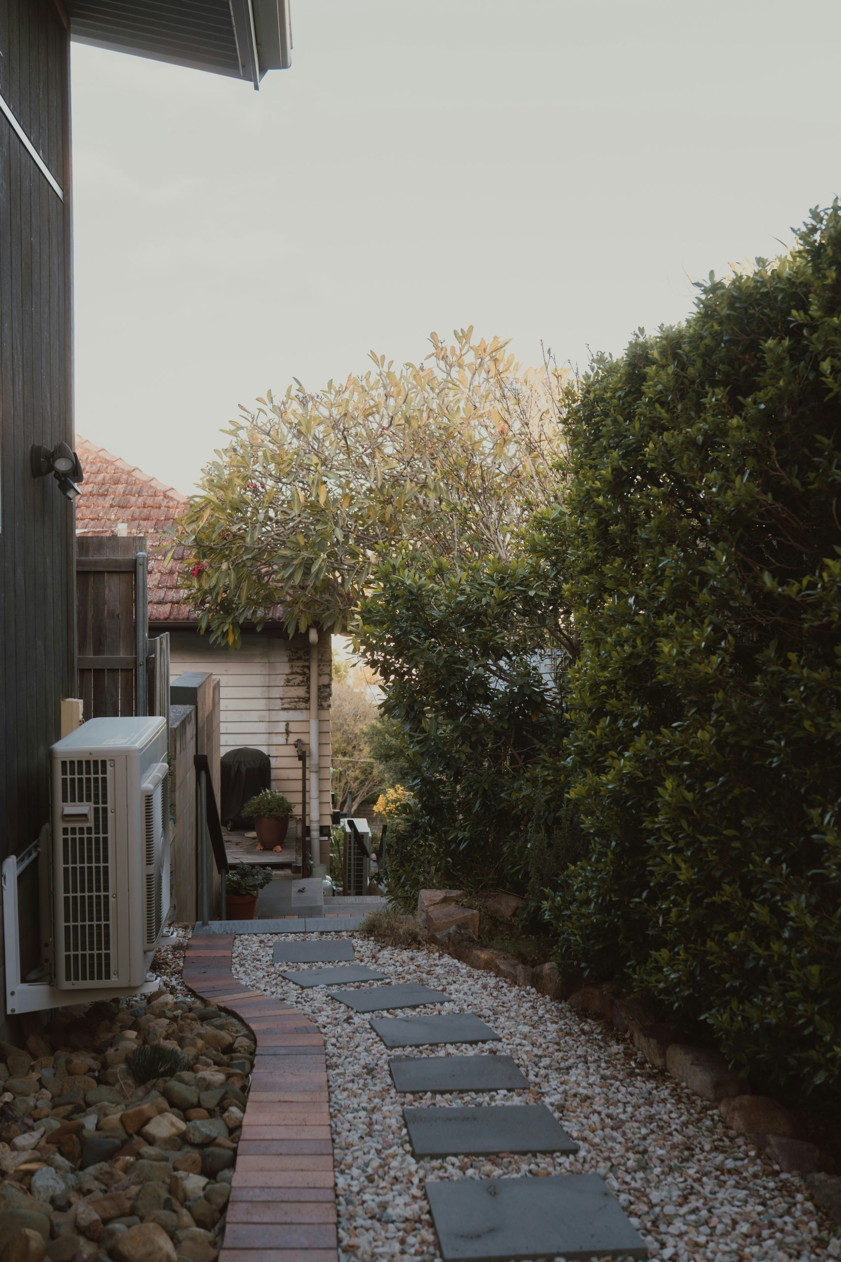 A narrow garden path with stepping stones and green bushes.