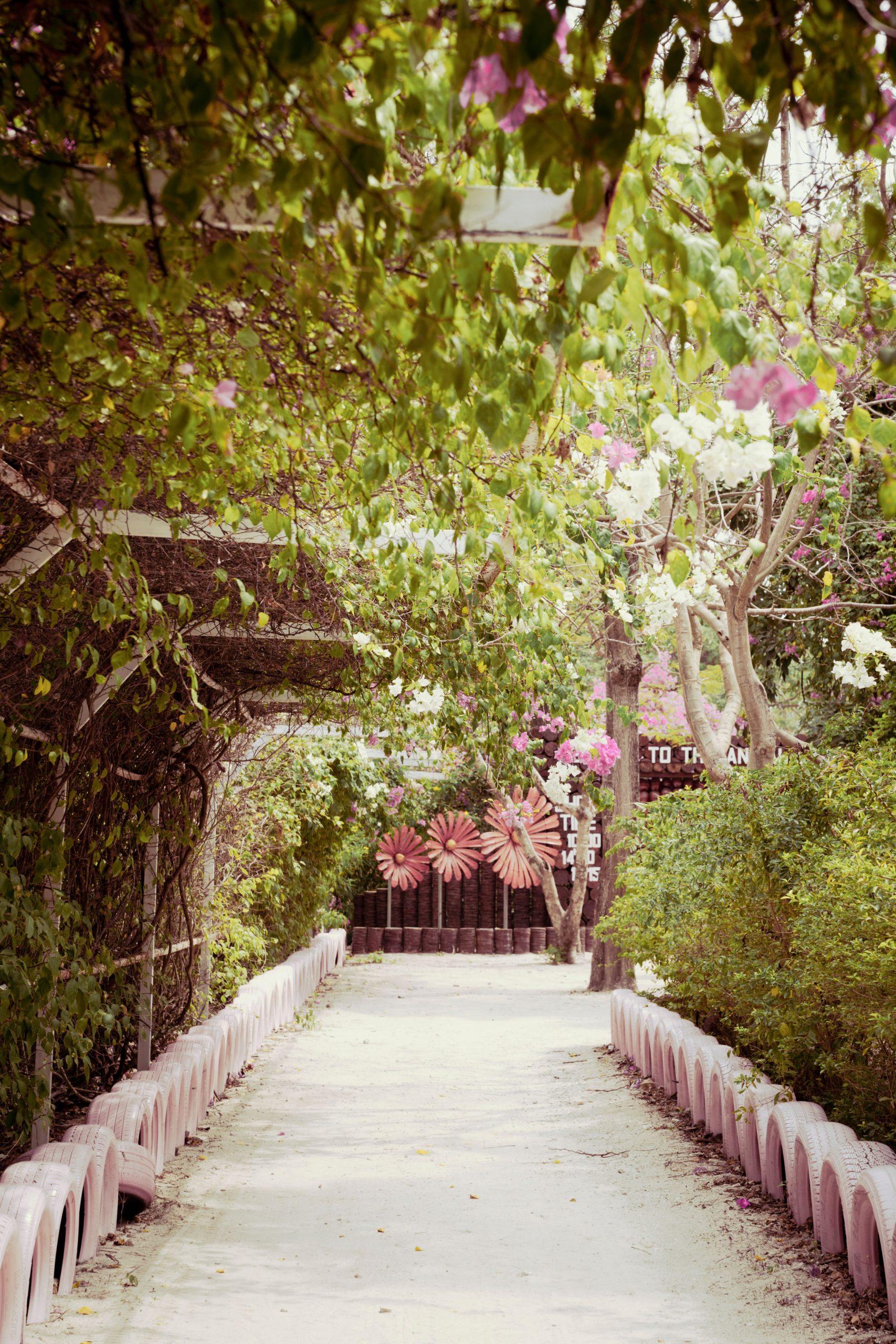 A peaceful path through a lush, flower-covered tunnel in a spring garden setting.