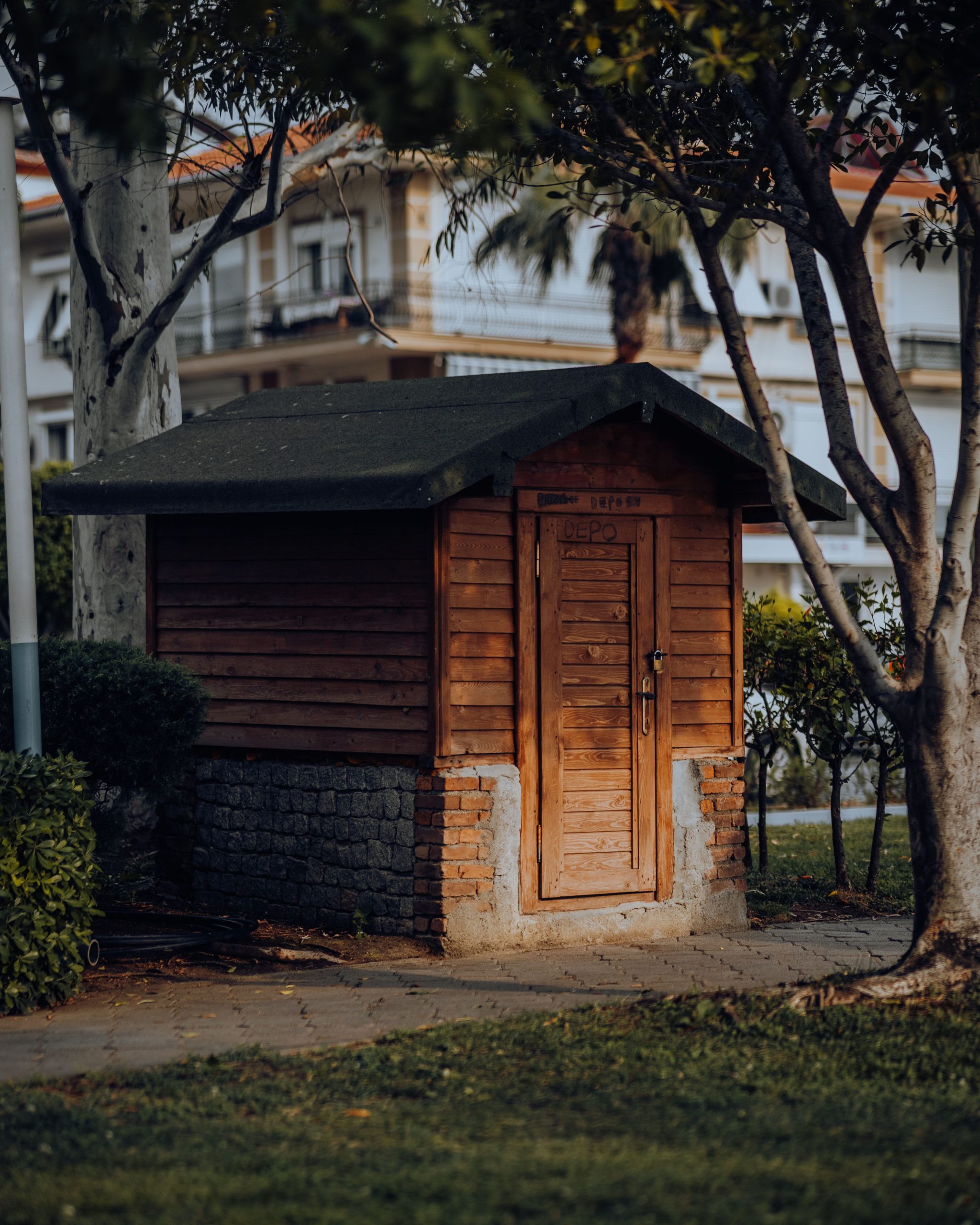 A quaint wooden shed nestled among trees with a rustic outdoor setting, perfect for gardening or storage.