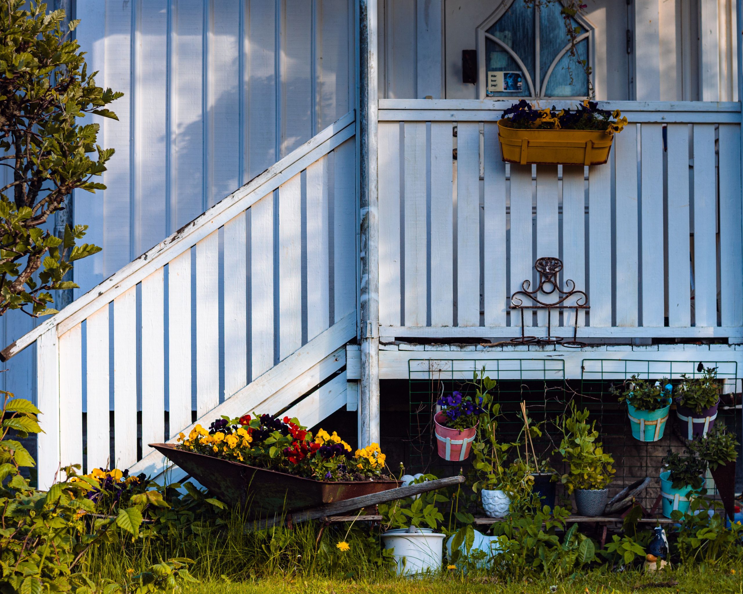 A rustic porch adorned with colorful flower pots and a charming wheelbarrow display.