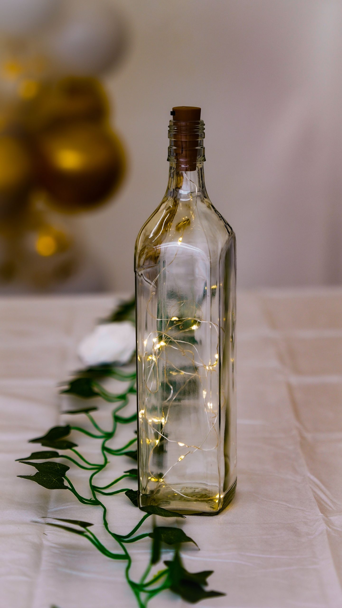 A stylish glass bottle enhances decor with twinkling fairy lights and a vine on a festive table.