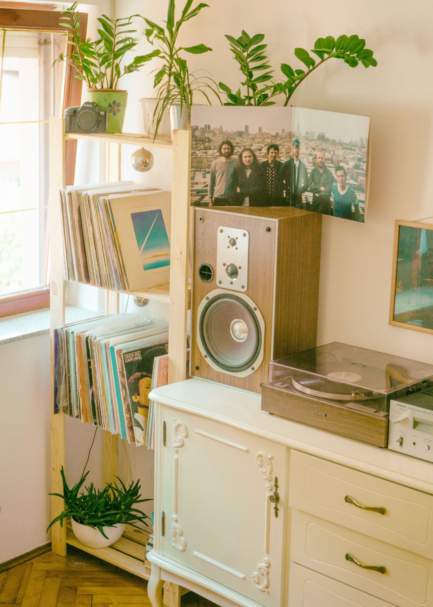 A stylish living room featuring a vintage turntable, vinyl records, plants, and retro decor.