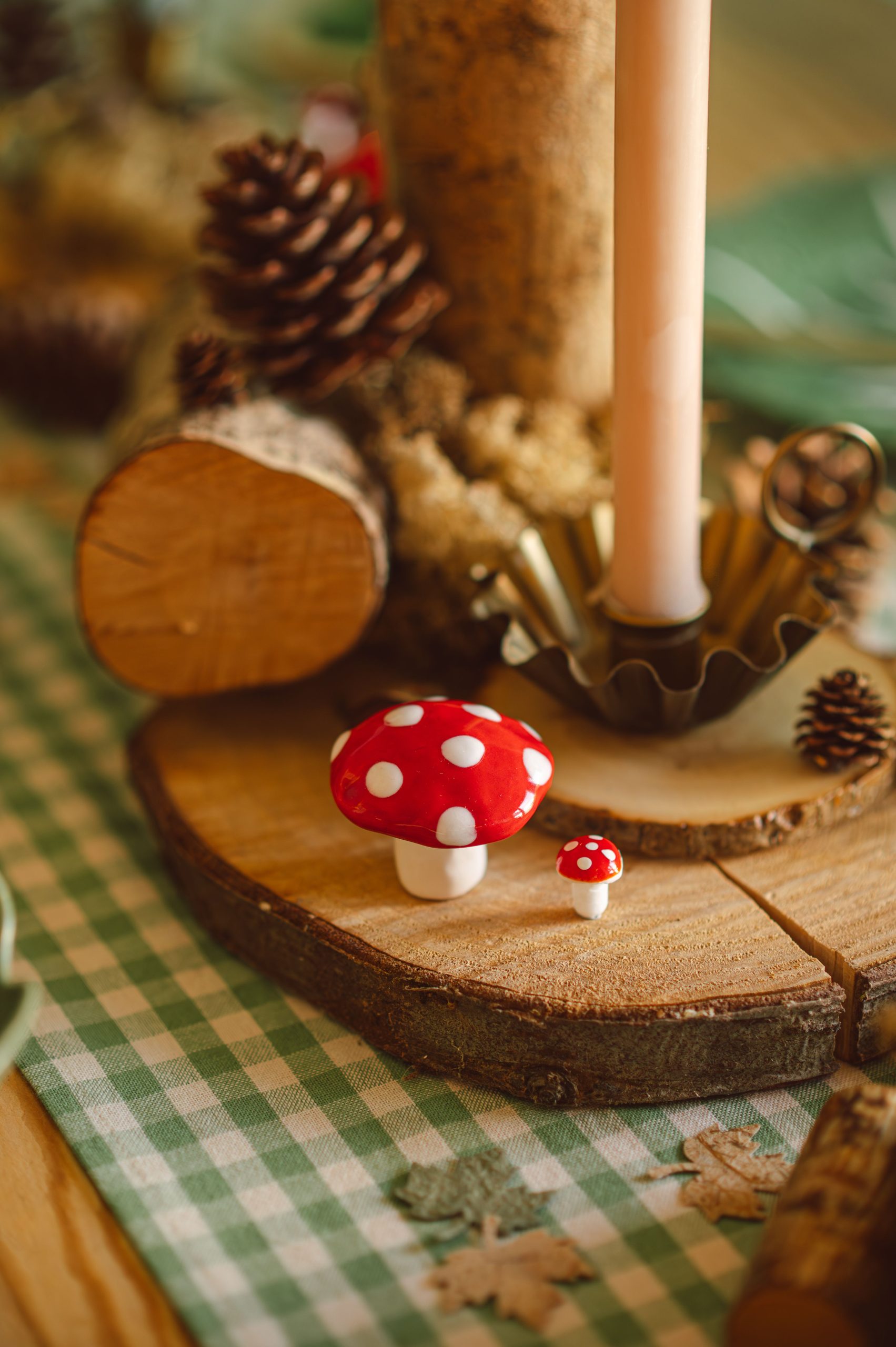 A warm and inviting autumn table setting featuring red mushrooms and pinecones.