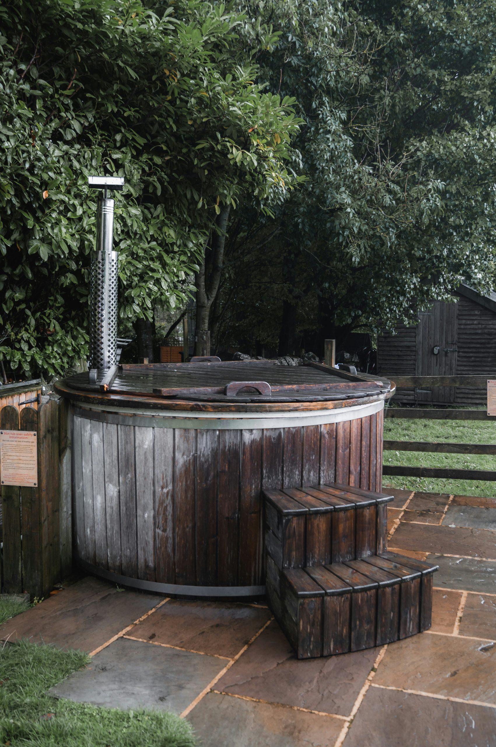 An outdoors hot tub, powered by a wood burner, in the forest.