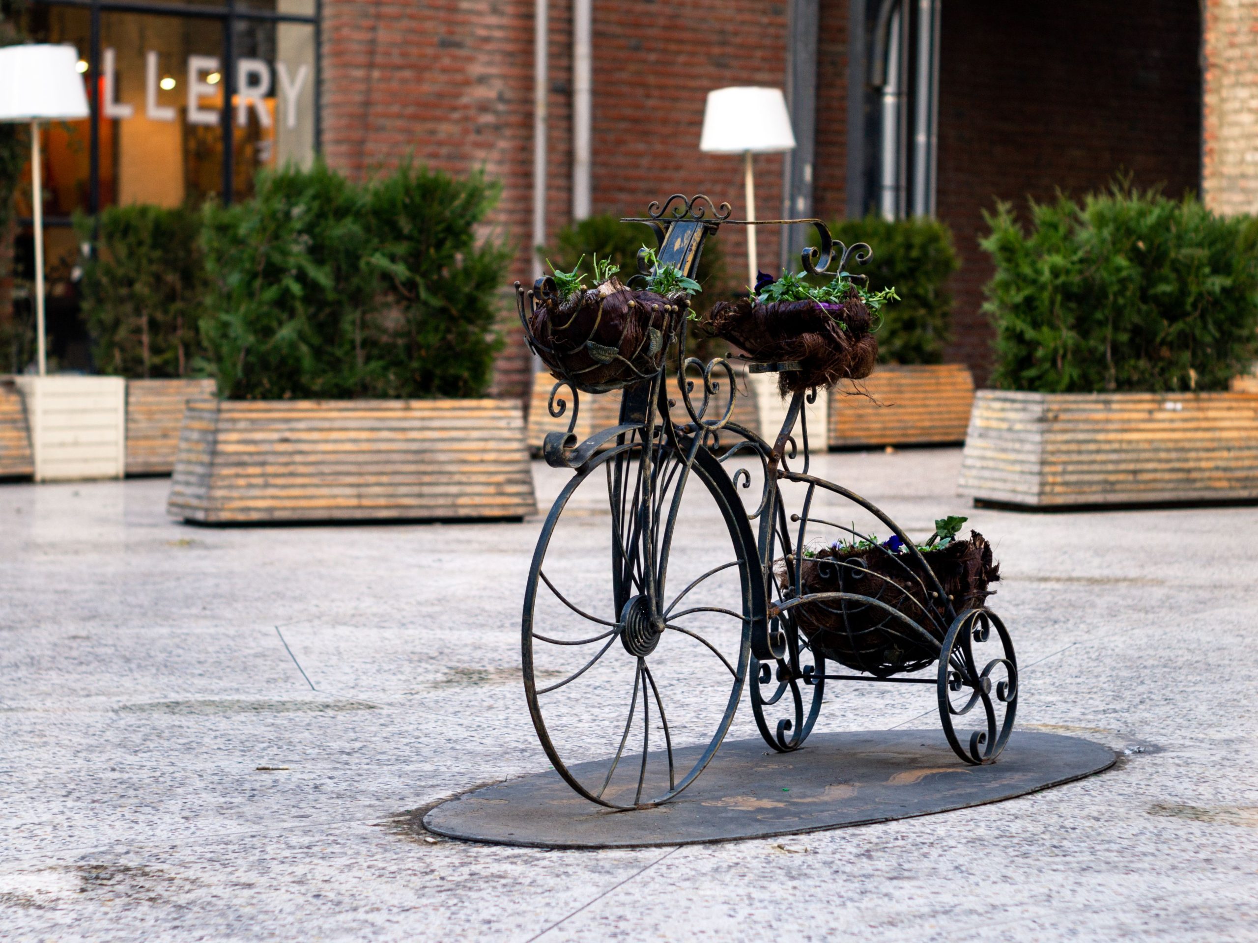 Artistic metal bike planter with flowers in an urban square, enhancing the public space decor.