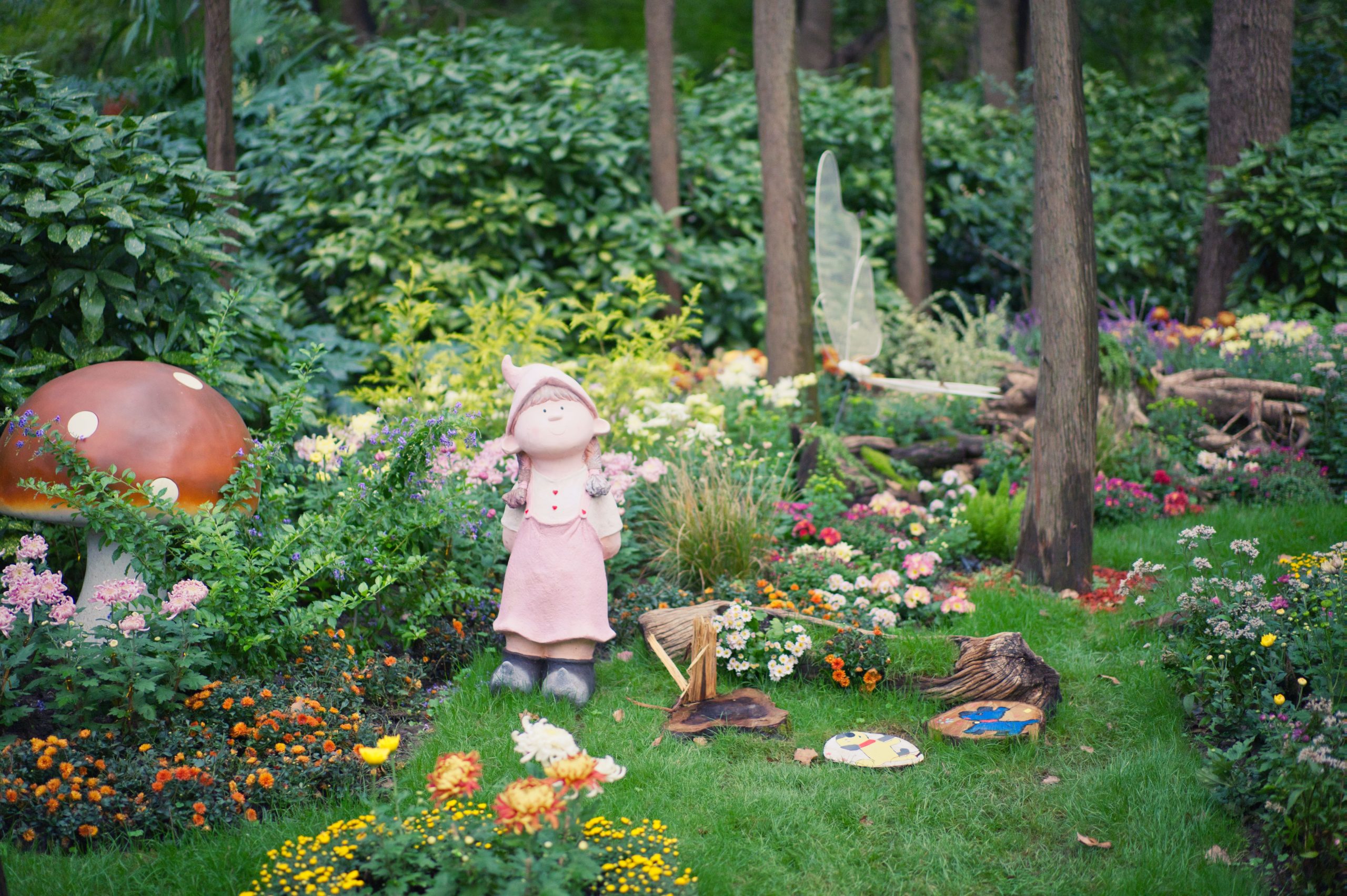 Charming garden scene with a fairy statue, mushroom, and colorful flowers.