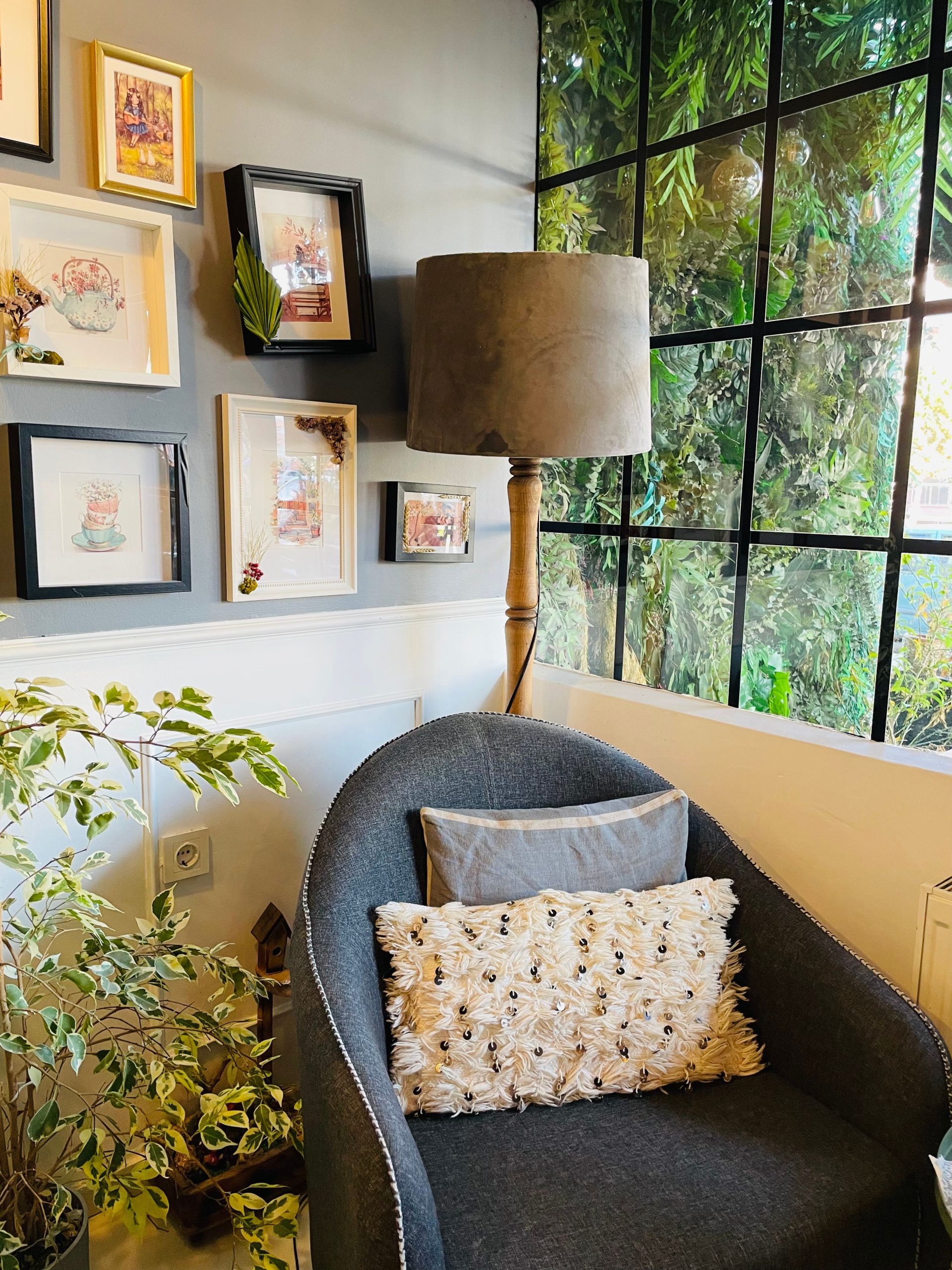 Charming living space featuring an armchair, floor lamp, and framed artwork by a window.