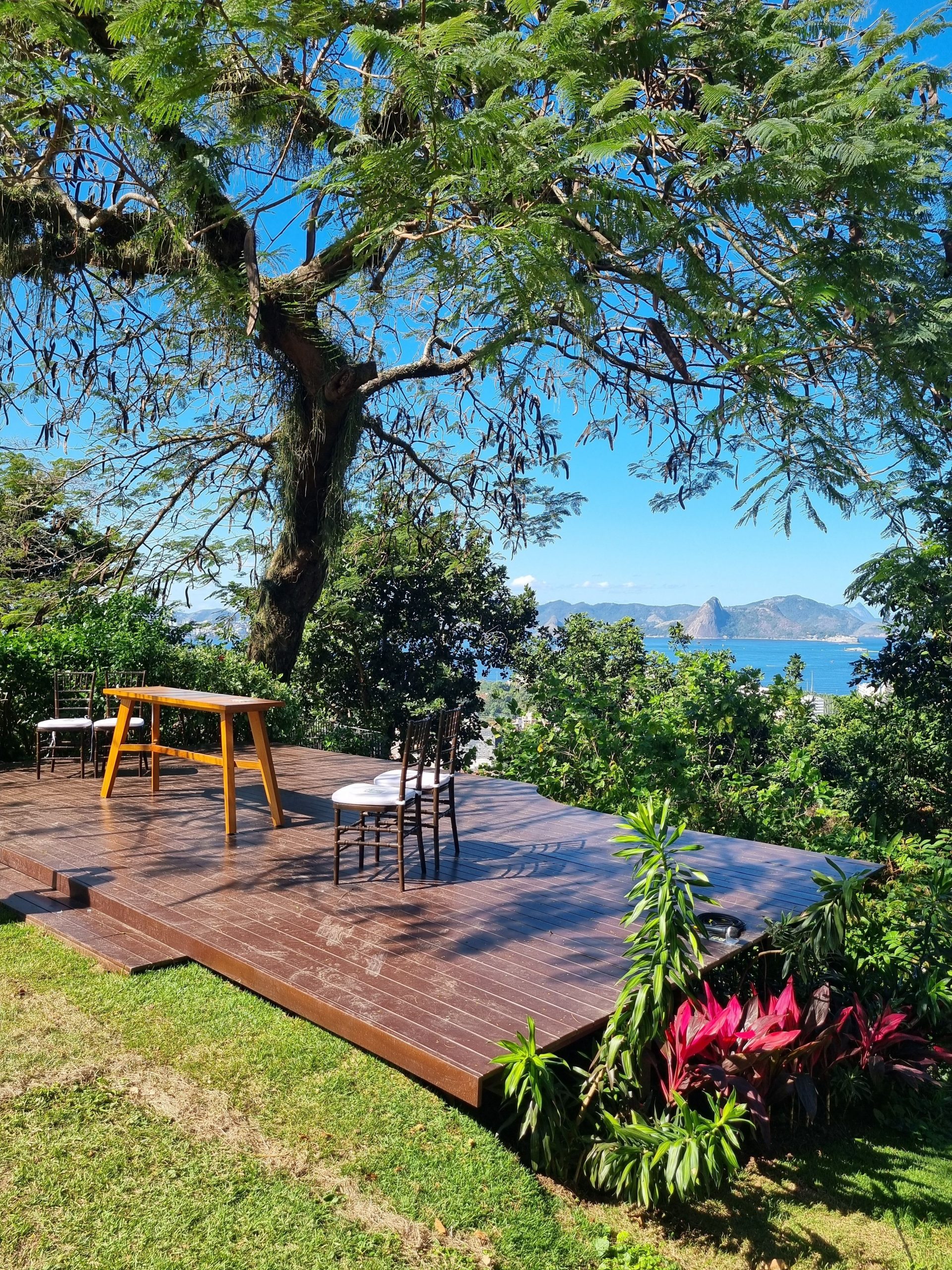 Charming outdoor patio with wooden deck and lush greenery overlooking the ocean in Rio de Janeiro.