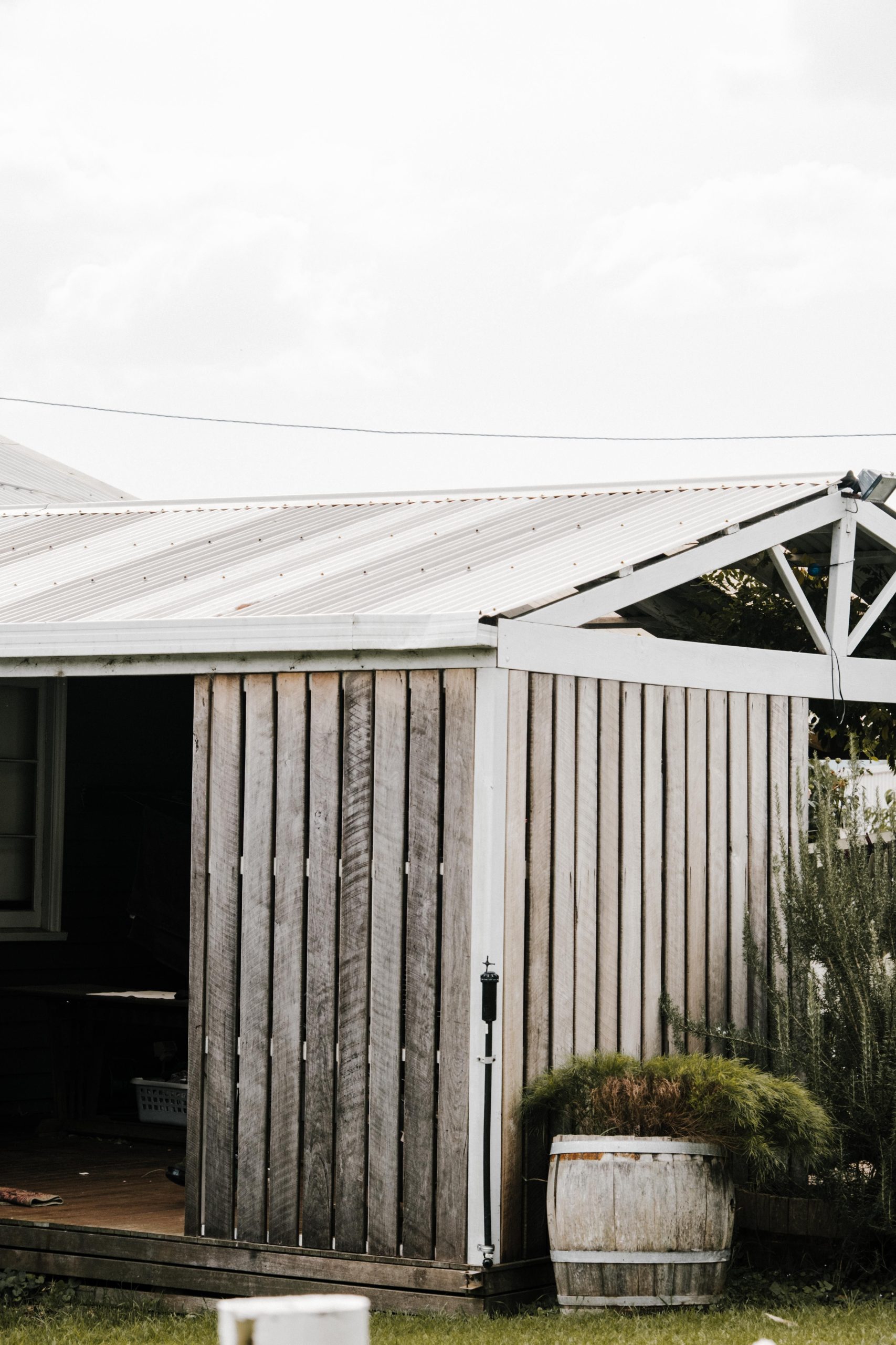 Charming rustic wooden shed with a barrel planter, set in an outdoor garden space, perfect for peaceful retreats.