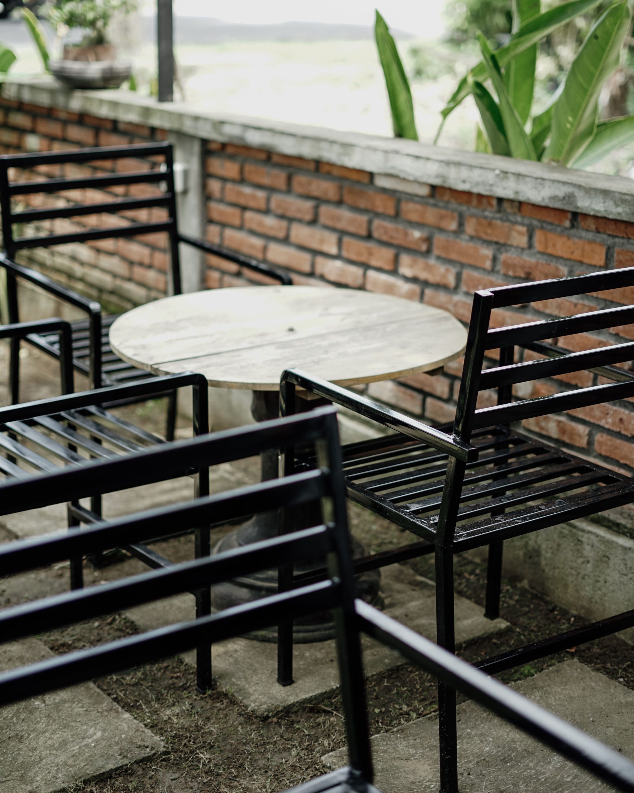 Cozy outdoor patio with black metal chairs and round wooden table, inviting ambiance.