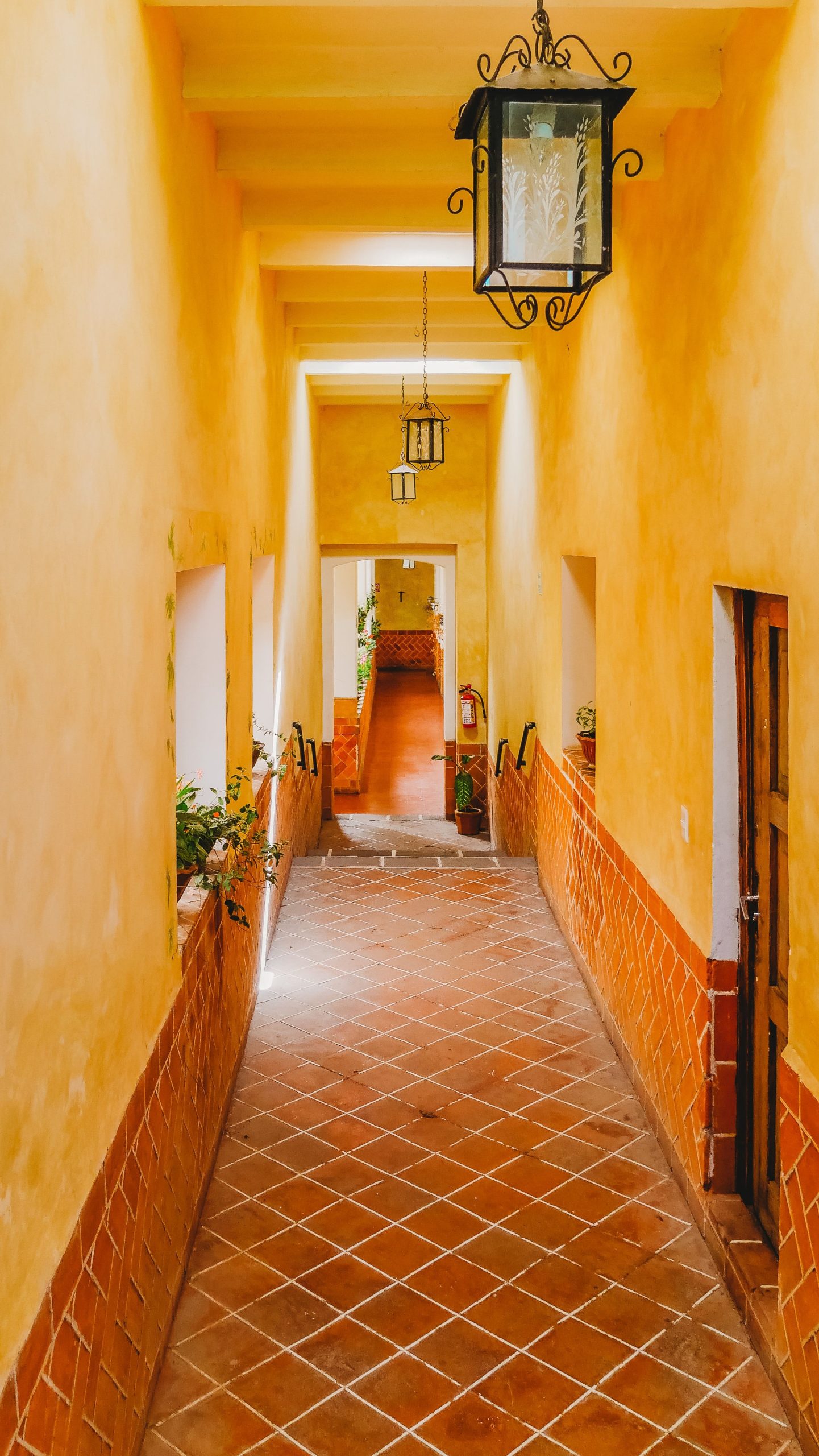 Elegant indoor corridor in Huamantla, Mexico, featuring classic terracotta tiles and rustic lanterns.