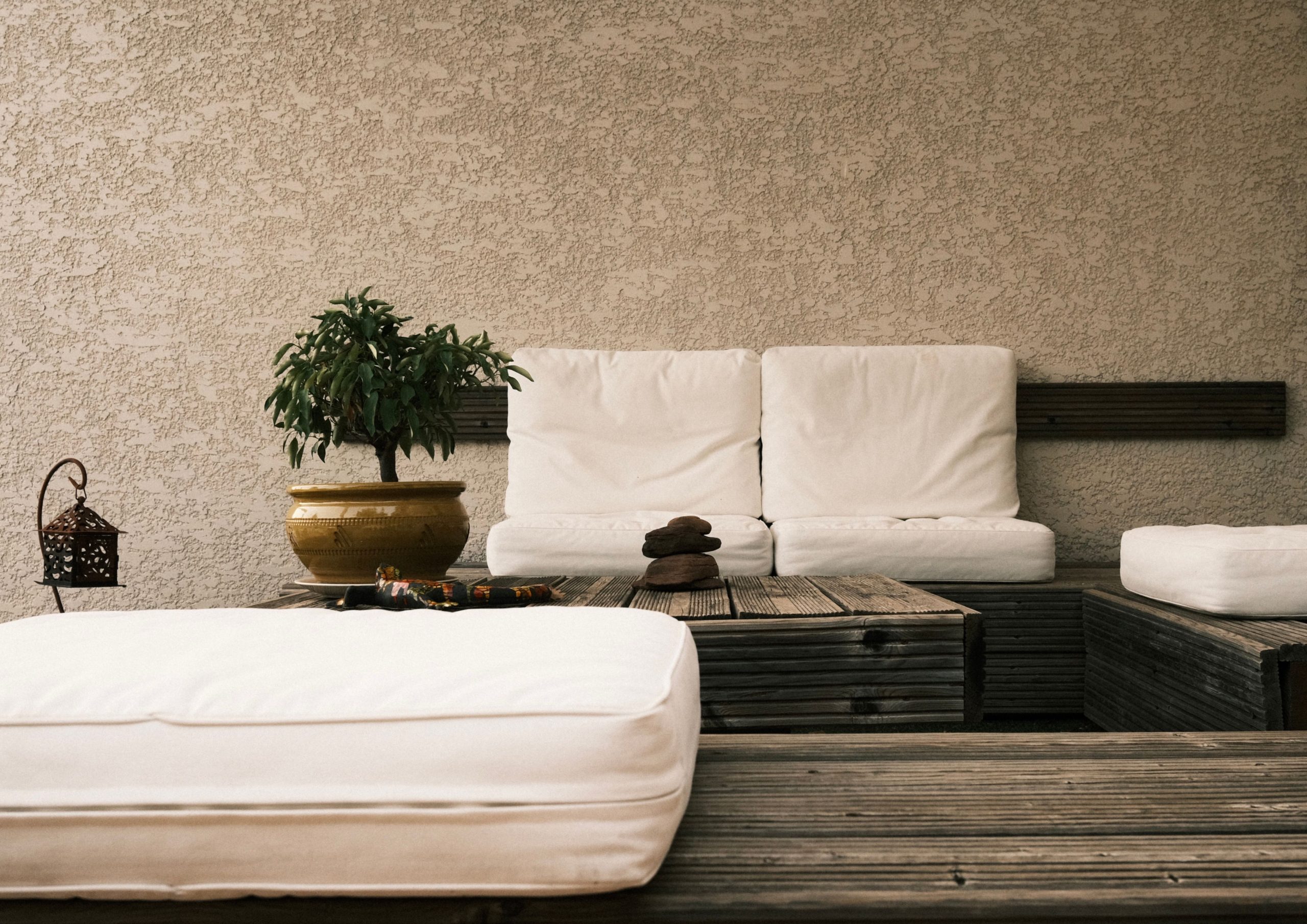 Inviting minimalist patio with white cushions and wooden decor in Occitanie, France.
