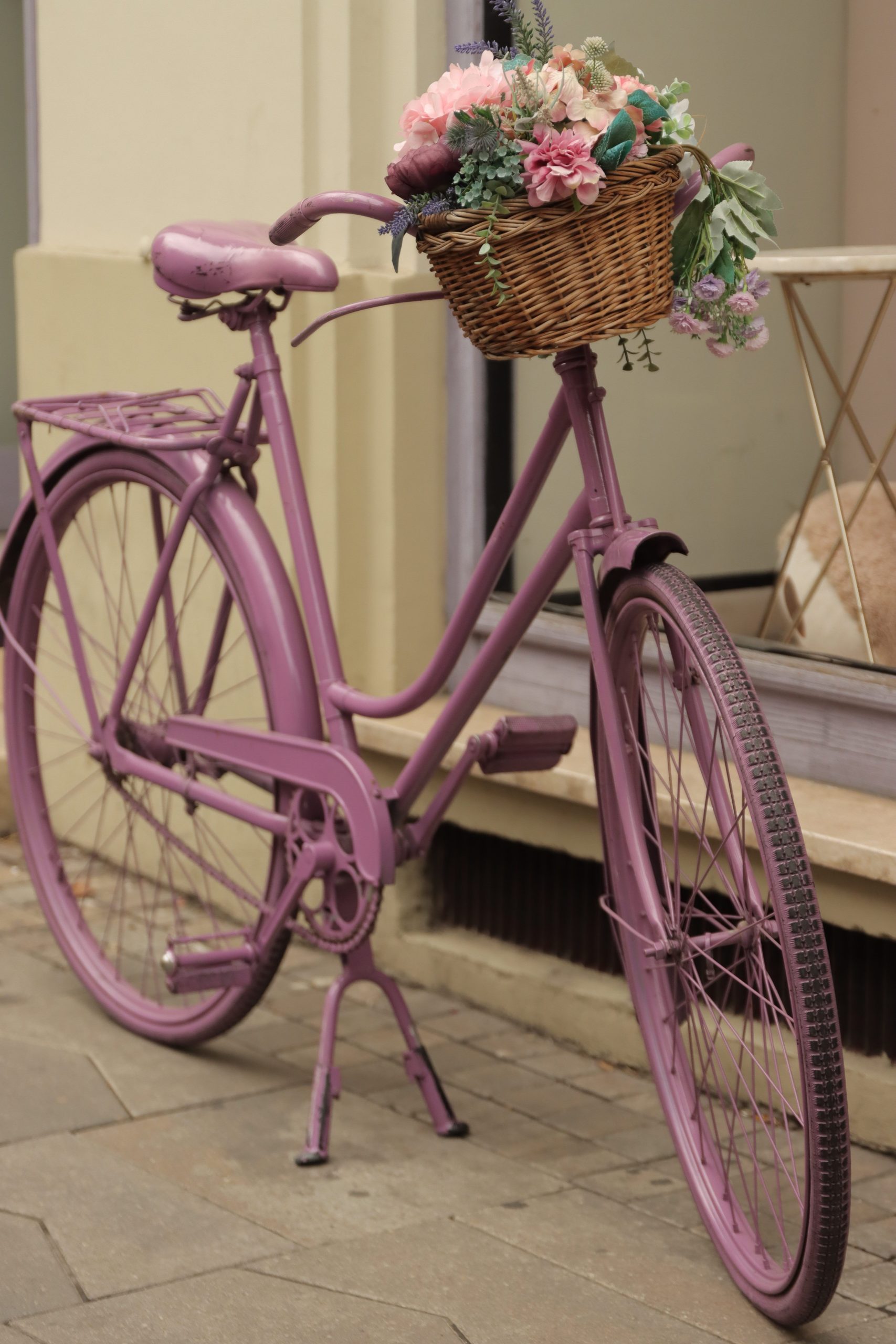 Vintage pink bicycle with a flower-filled basket on a Budapest sidewalk, offering a charming urban scene.