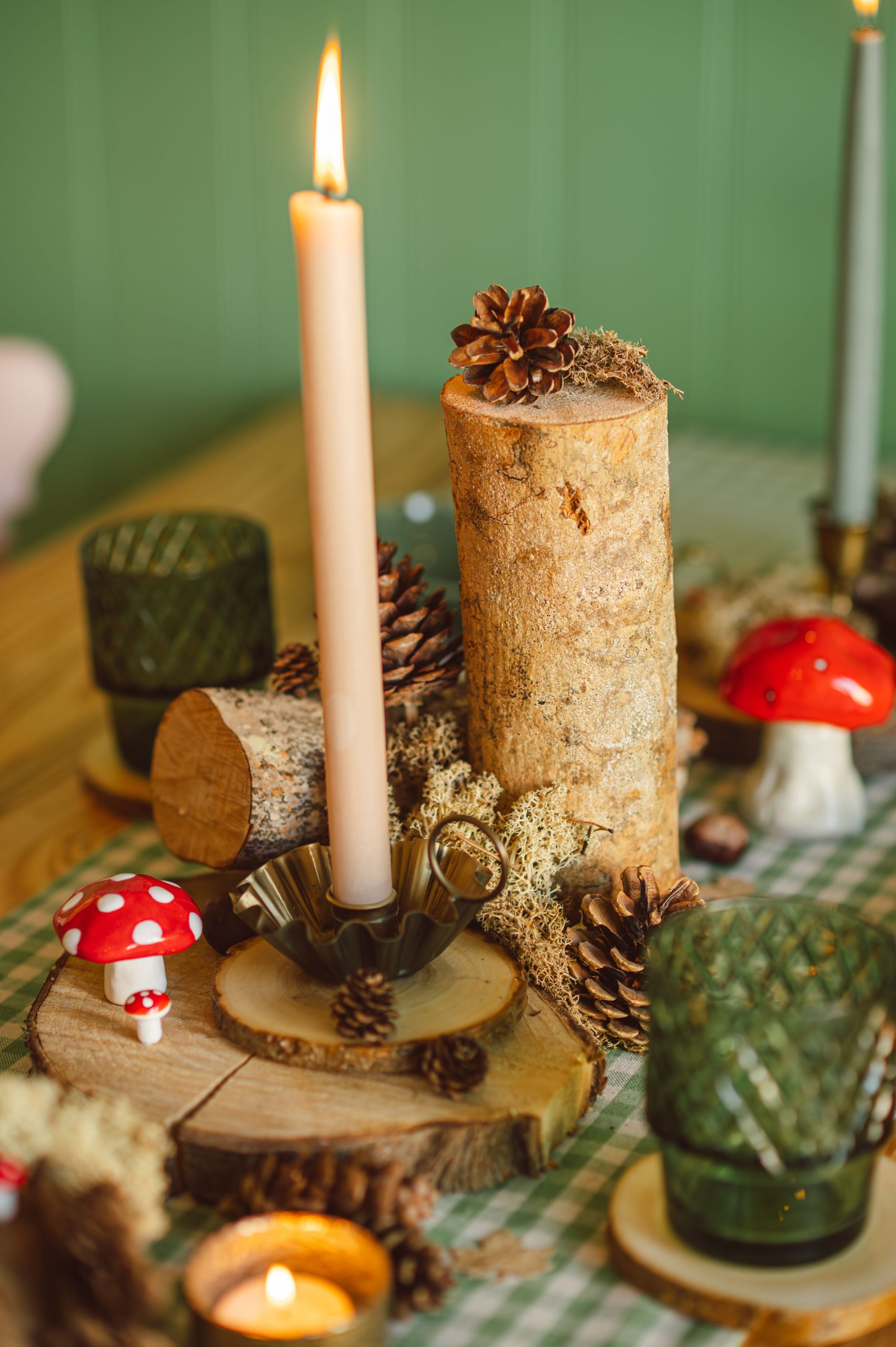 Warm and inviting autumn table setting featuring candles, pinecones, and rustic elements.