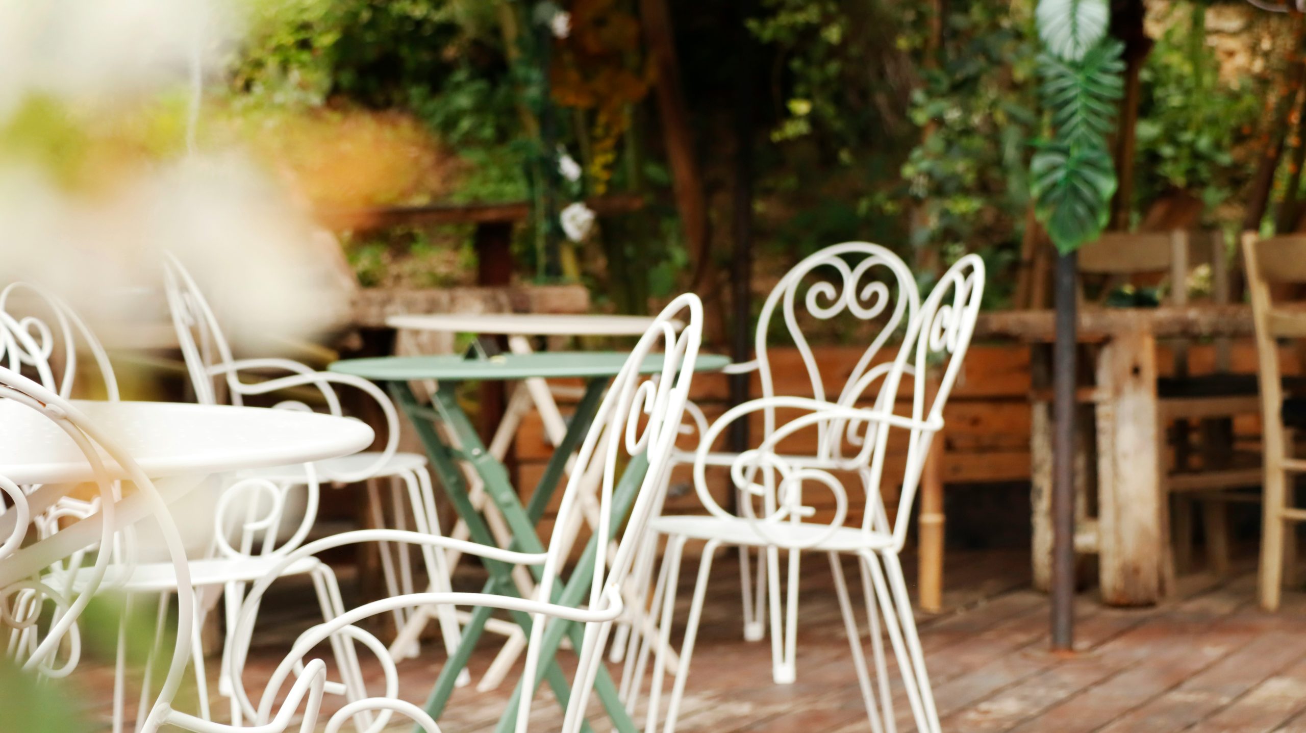 White metal chairs and tables on a wooden deck.