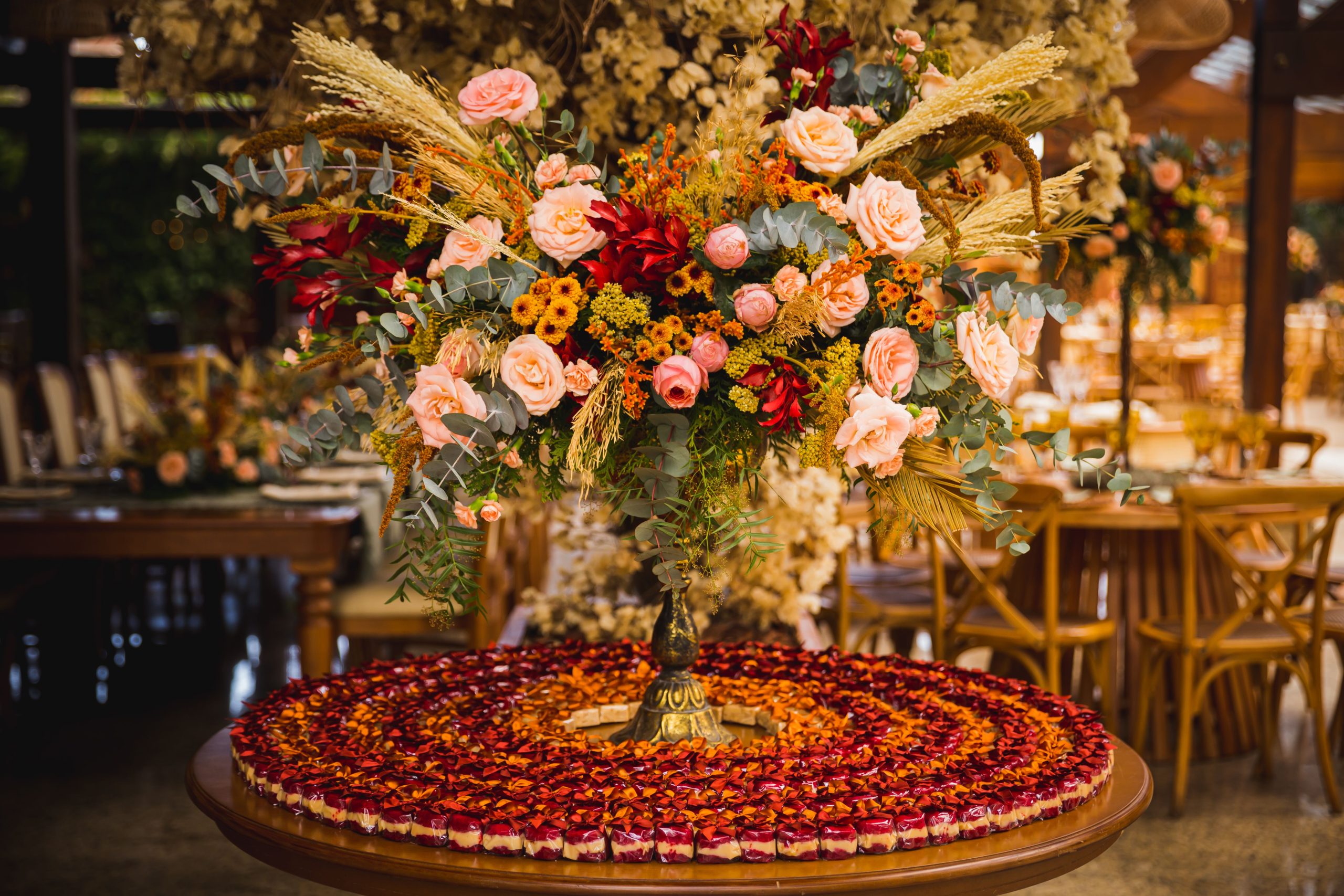 A beautiful floral centerpiece with roses and dried flowers on a round table in an elegant setting.