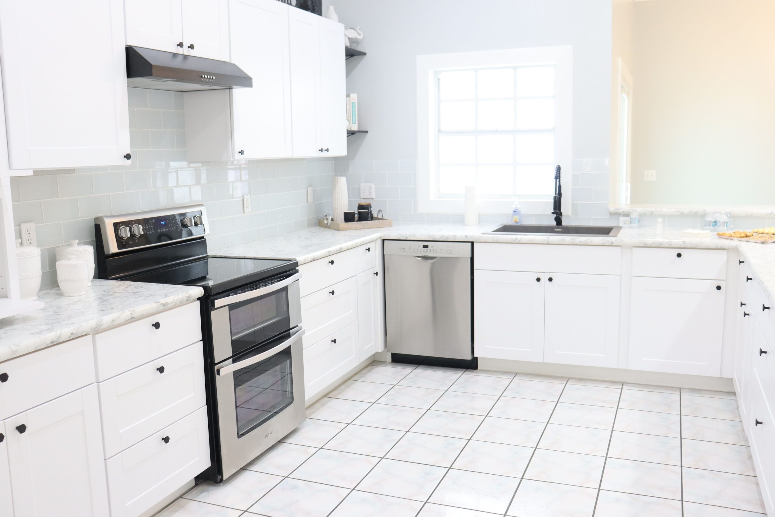A bright and spacious modern kitchen with white cabinets, appliances, and natural light.