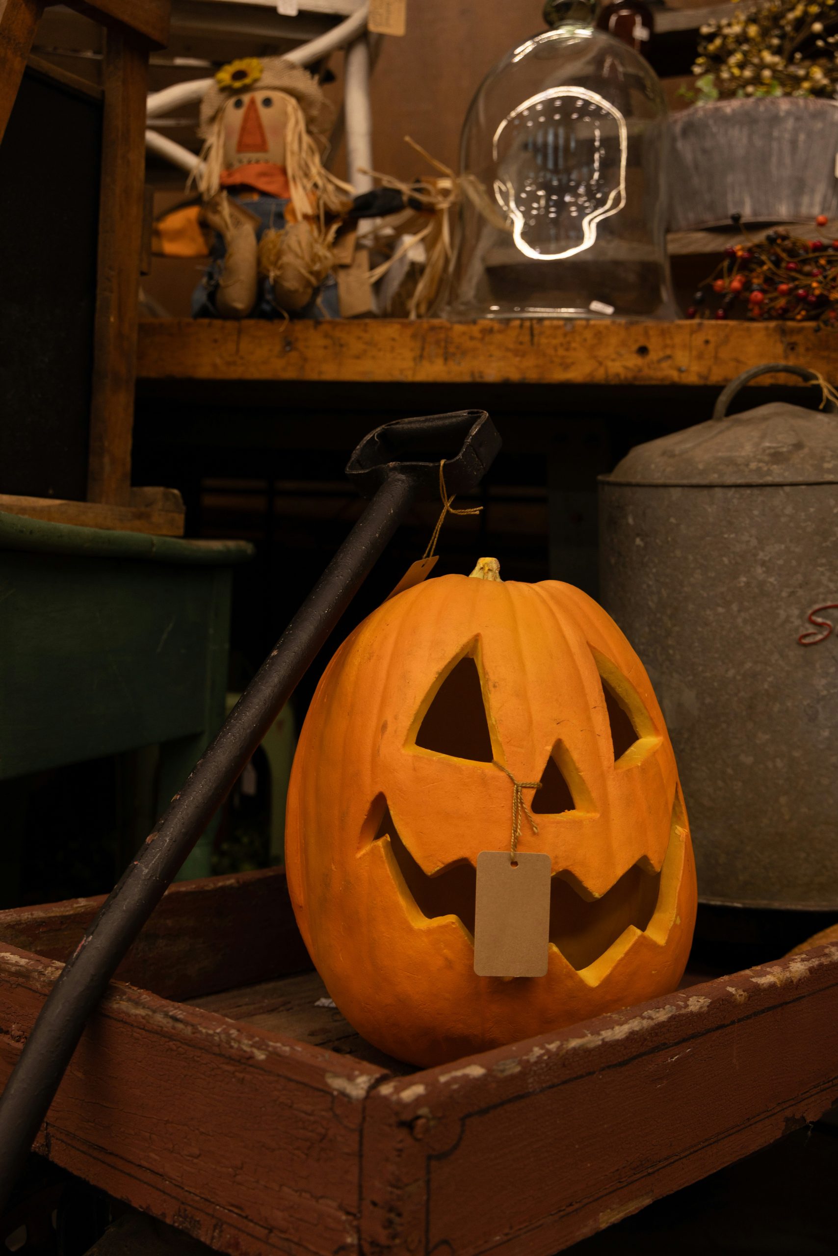 A cheerful jack-o’-lantern rests in a worn wooden cart at a flea market stall filled with quirky autumn treasures and Halloween charm.