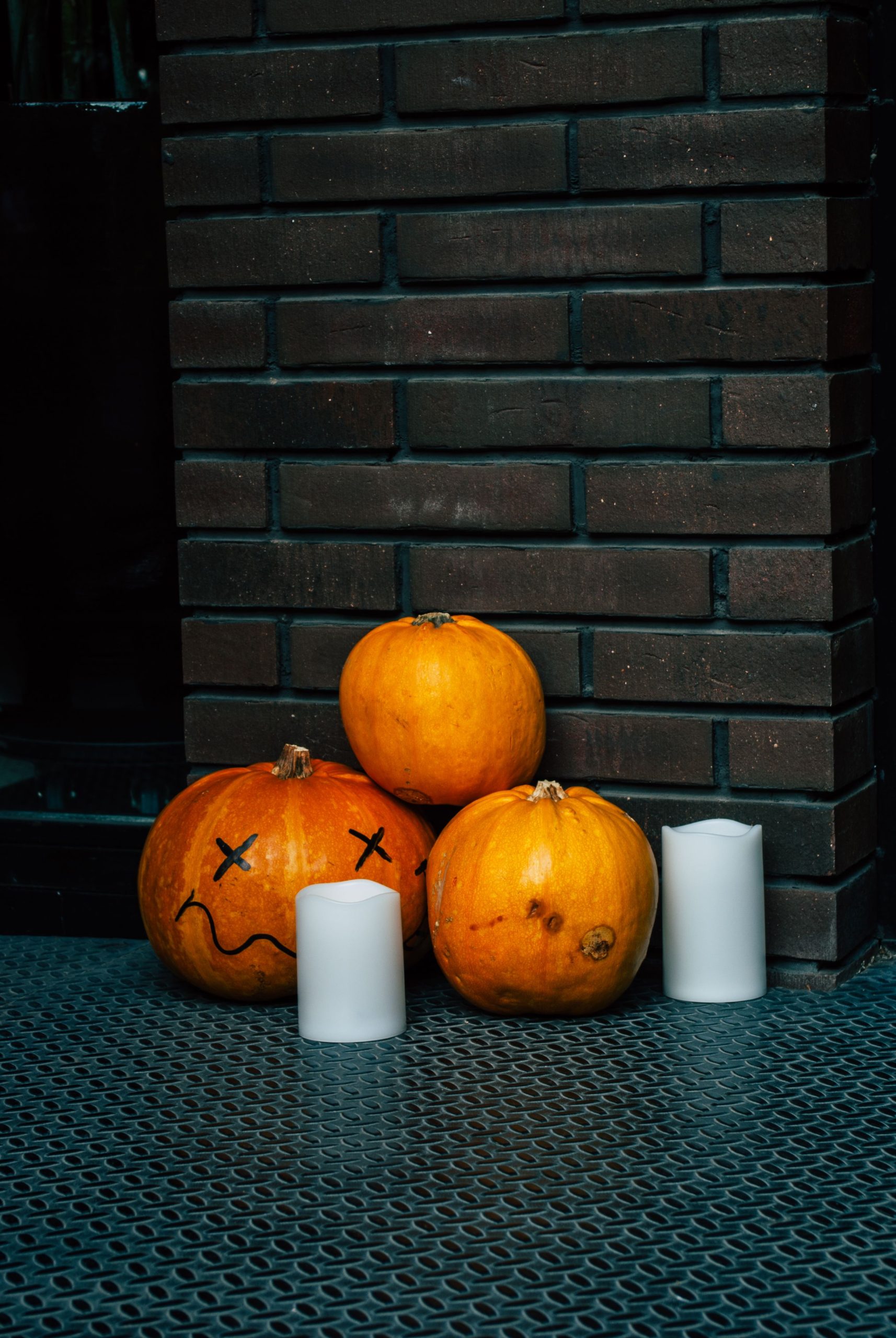A collection of carved pumpkins and candles against a brick wall, perfect for Halloween.
