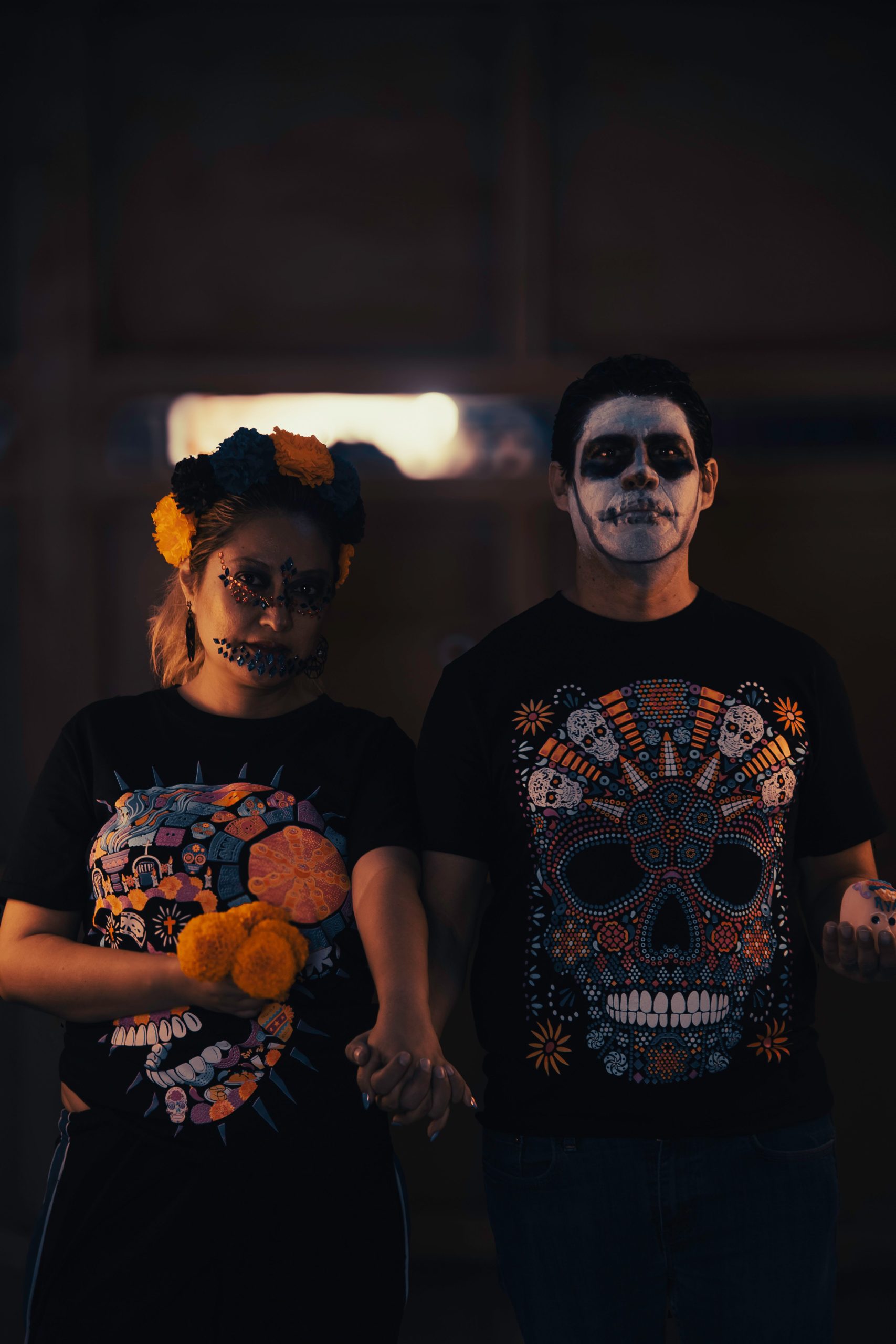 A couple celebrates Day of the Dead in colorful face paint and themed attire.