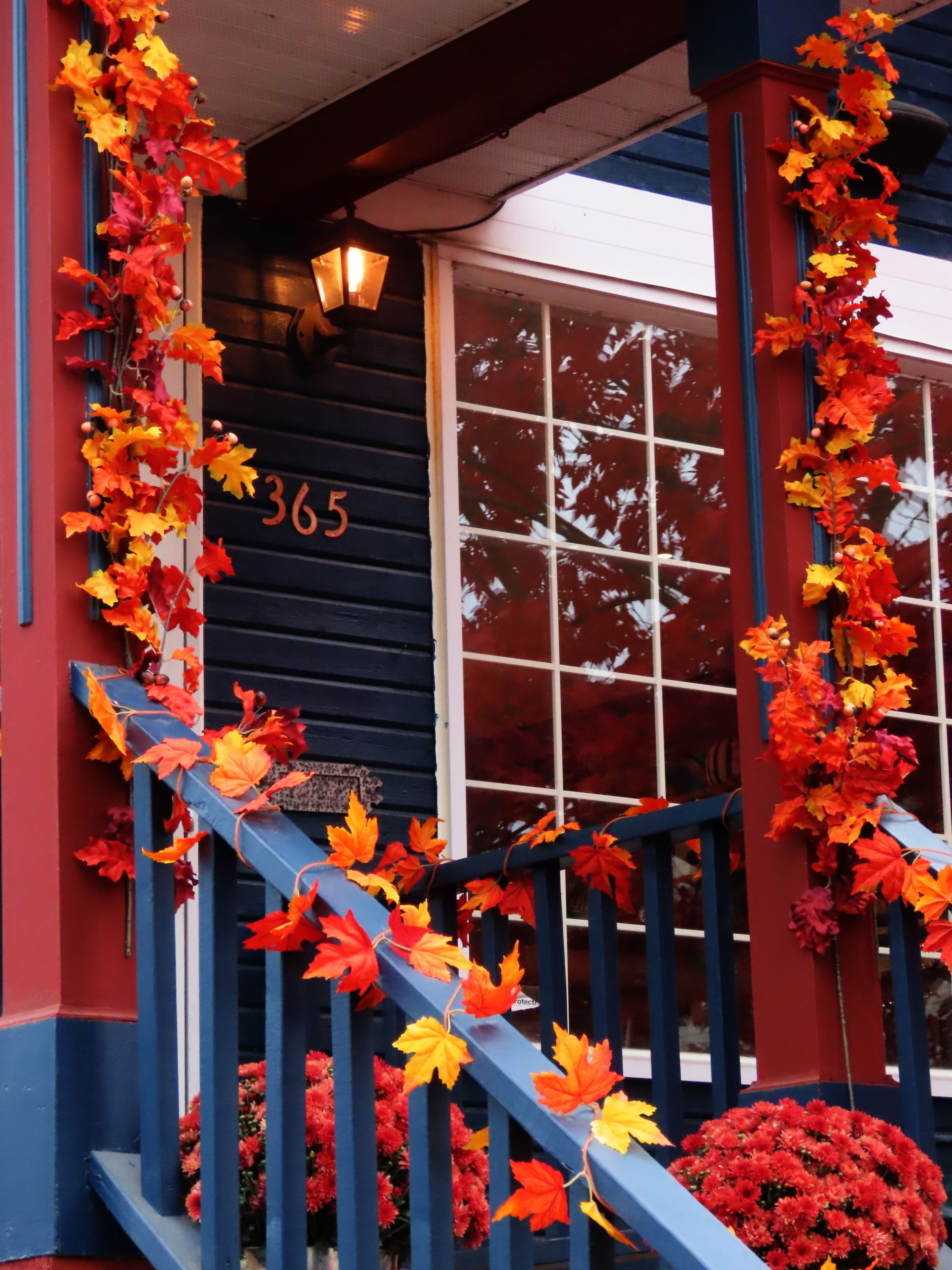 A cozy front porch adorned with vibrant fall maple leaves and warm lighting.
