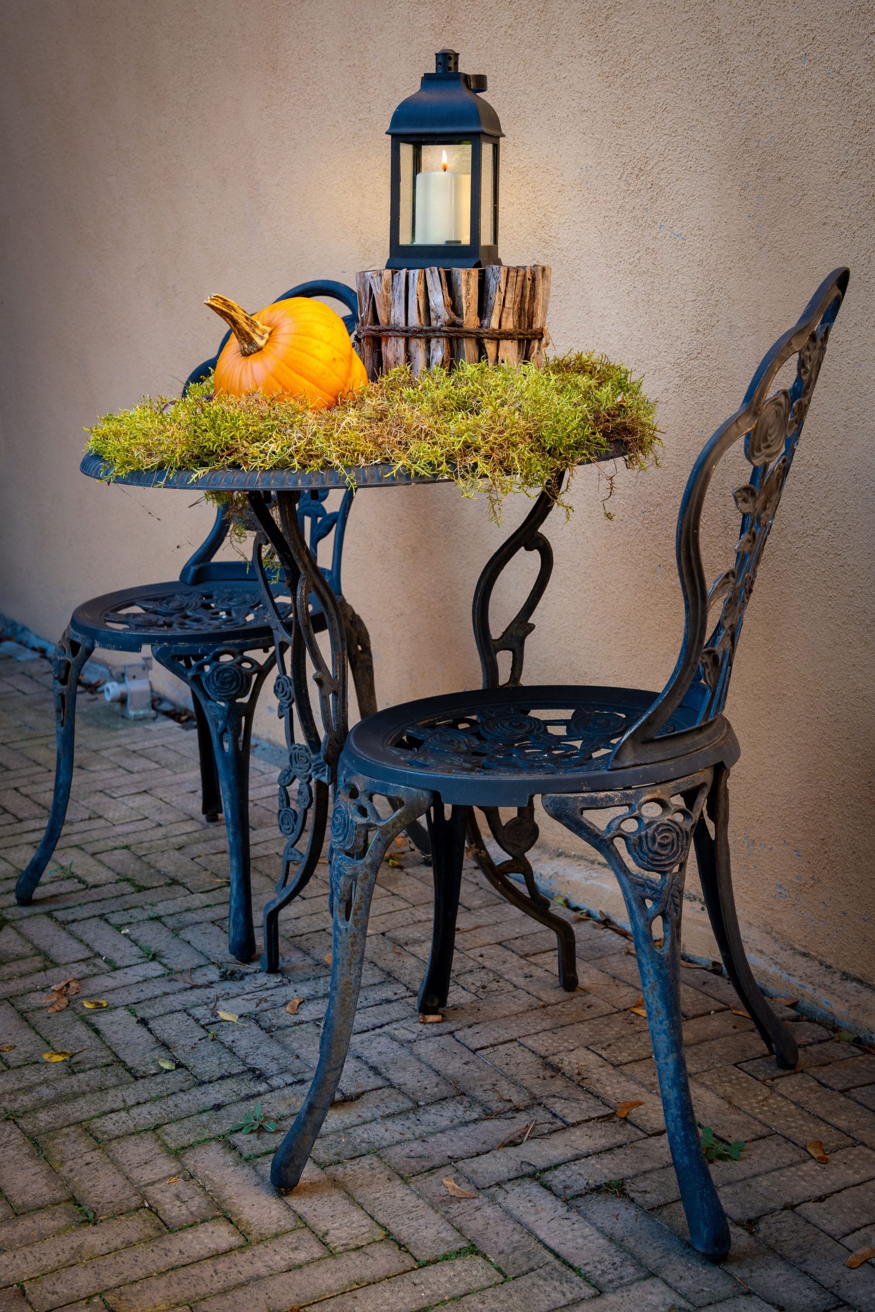 A cozy outdoor setup featuring a pumpkin and lantern on an elegant patio table, perfect for autumn.