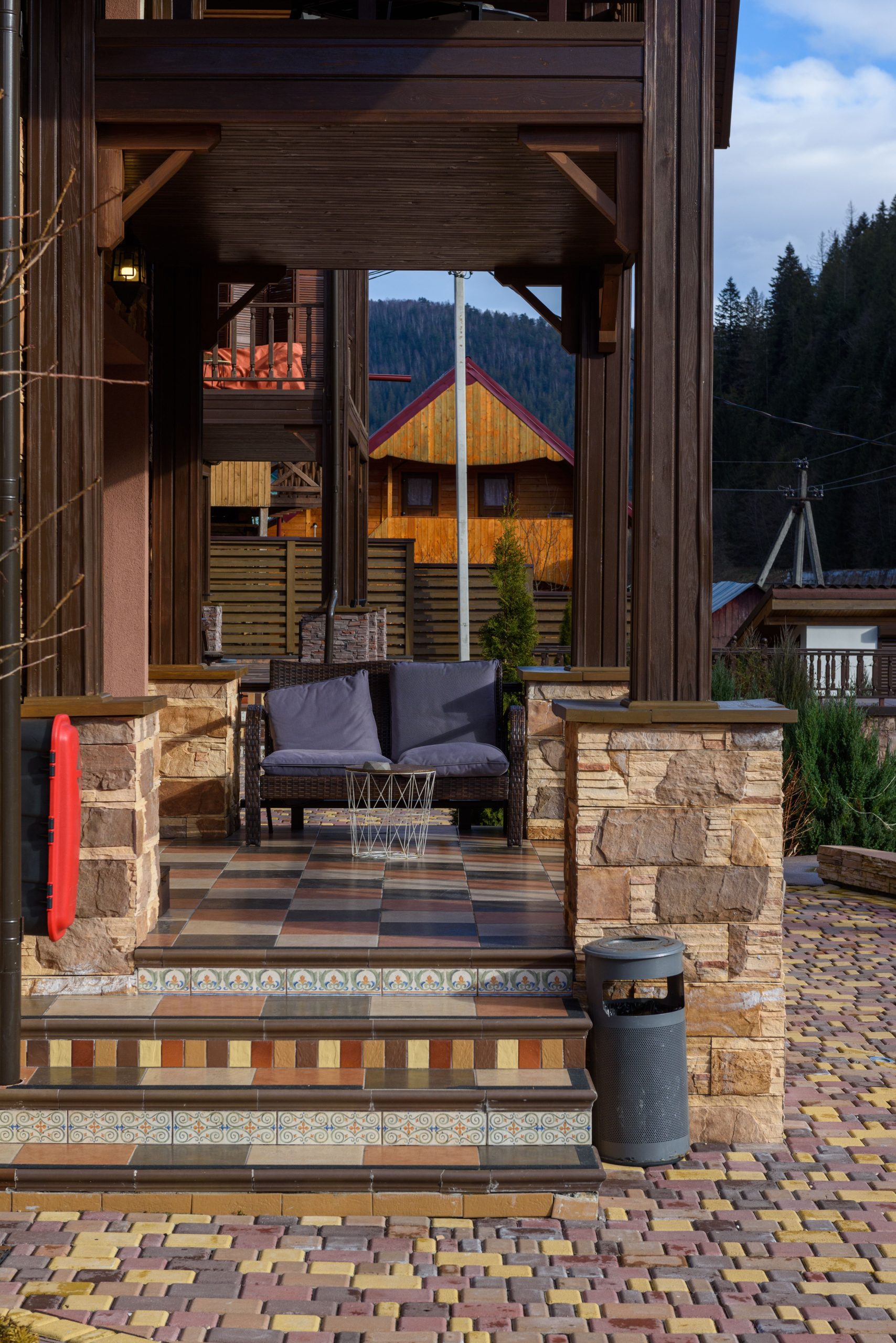 A cozy rustic porch with seating, nestled in a mountain village with scenic views.