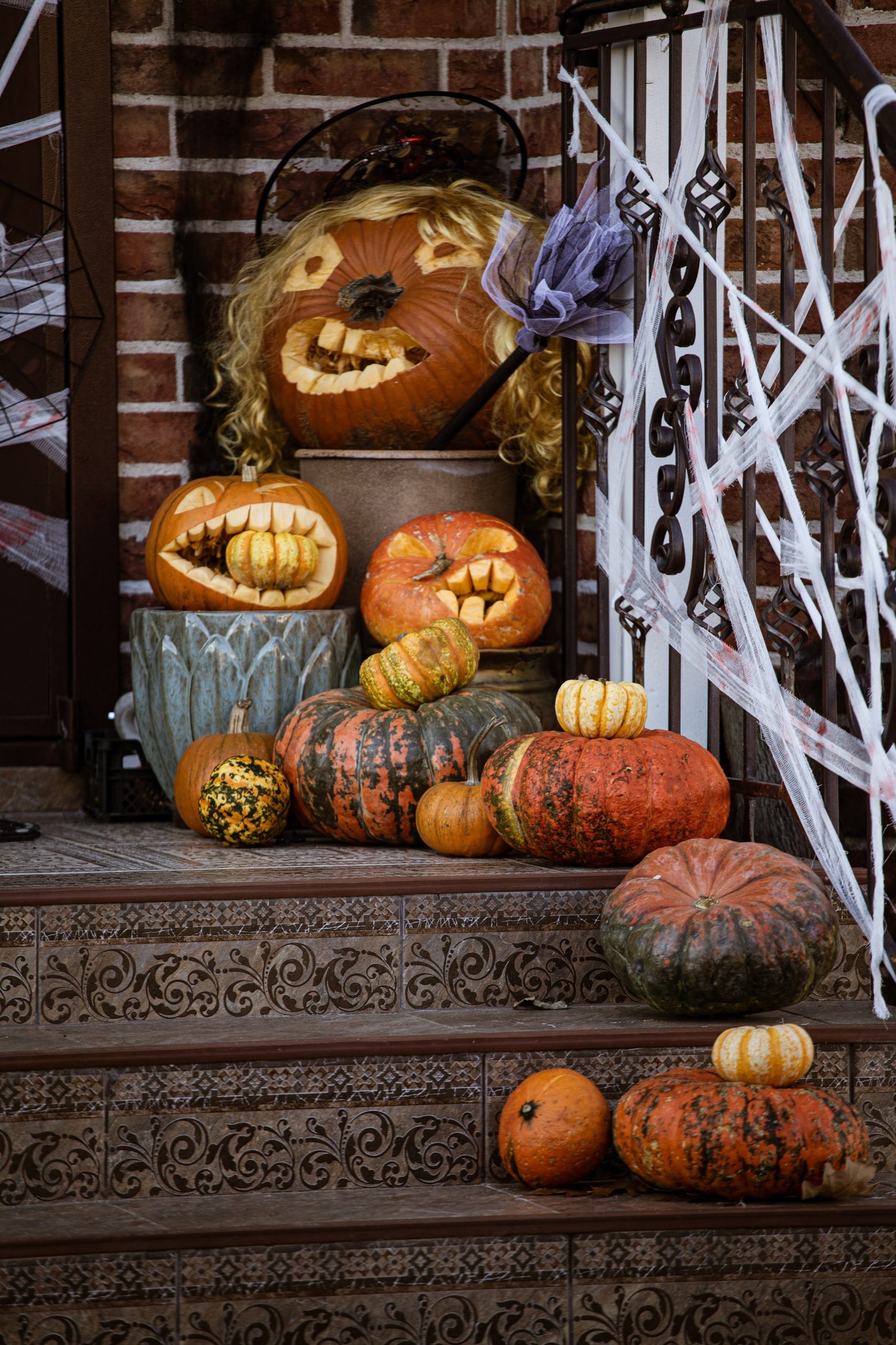 A creative display of carved pumpkins and gourds on a decorated staircase, perfect for Halloween ambiance.