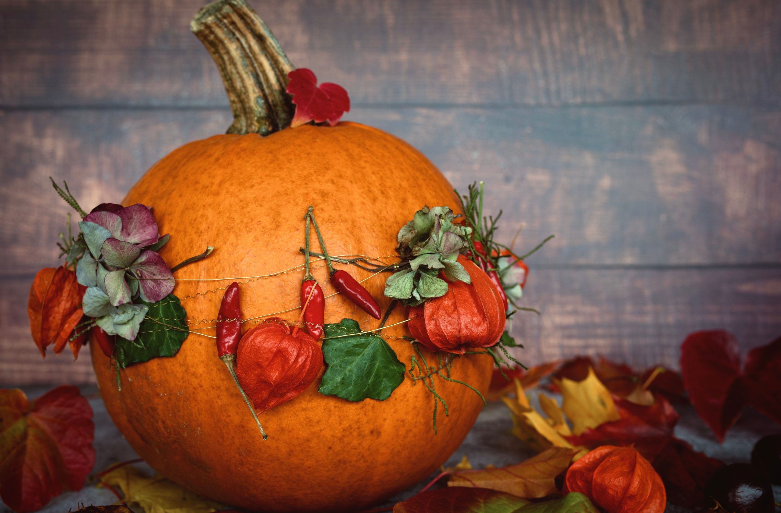 A decorated pumpkin adorned with leaves and flowers, capturing the essence of autumn.
