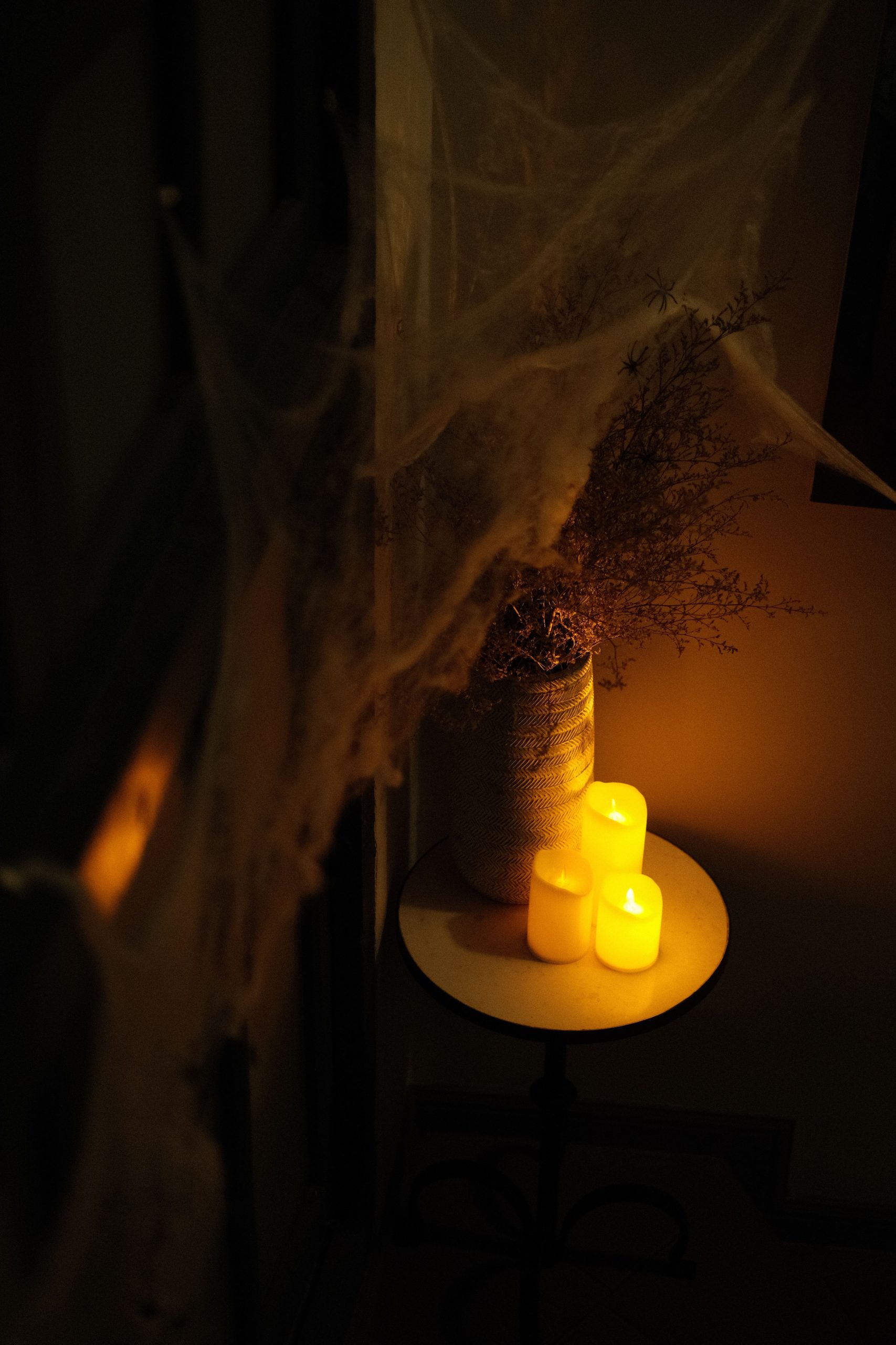 A dimly lit setup with candles and cobwebs, evoking a spooky Halloween ambiance.