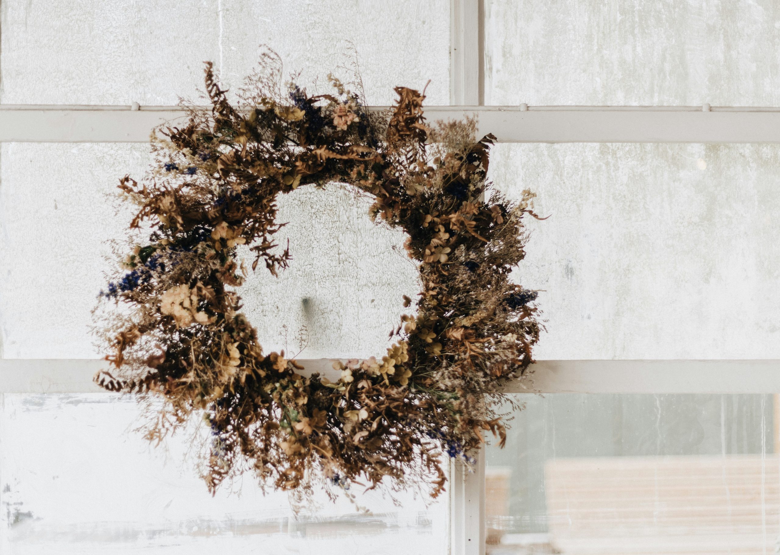 A dried wreath hanging on a window sill