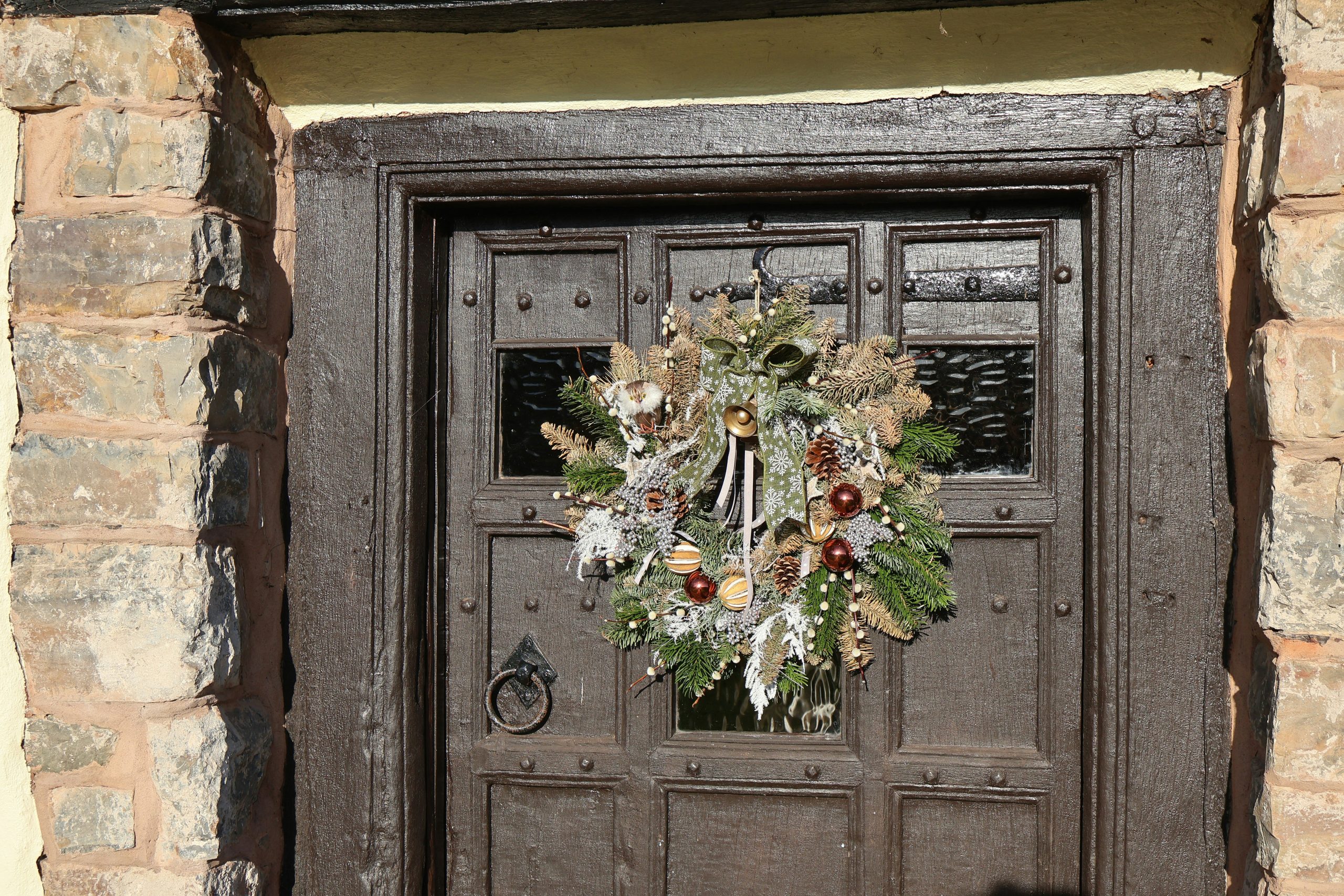 A festive wreath hangs on a rustic wooden door
