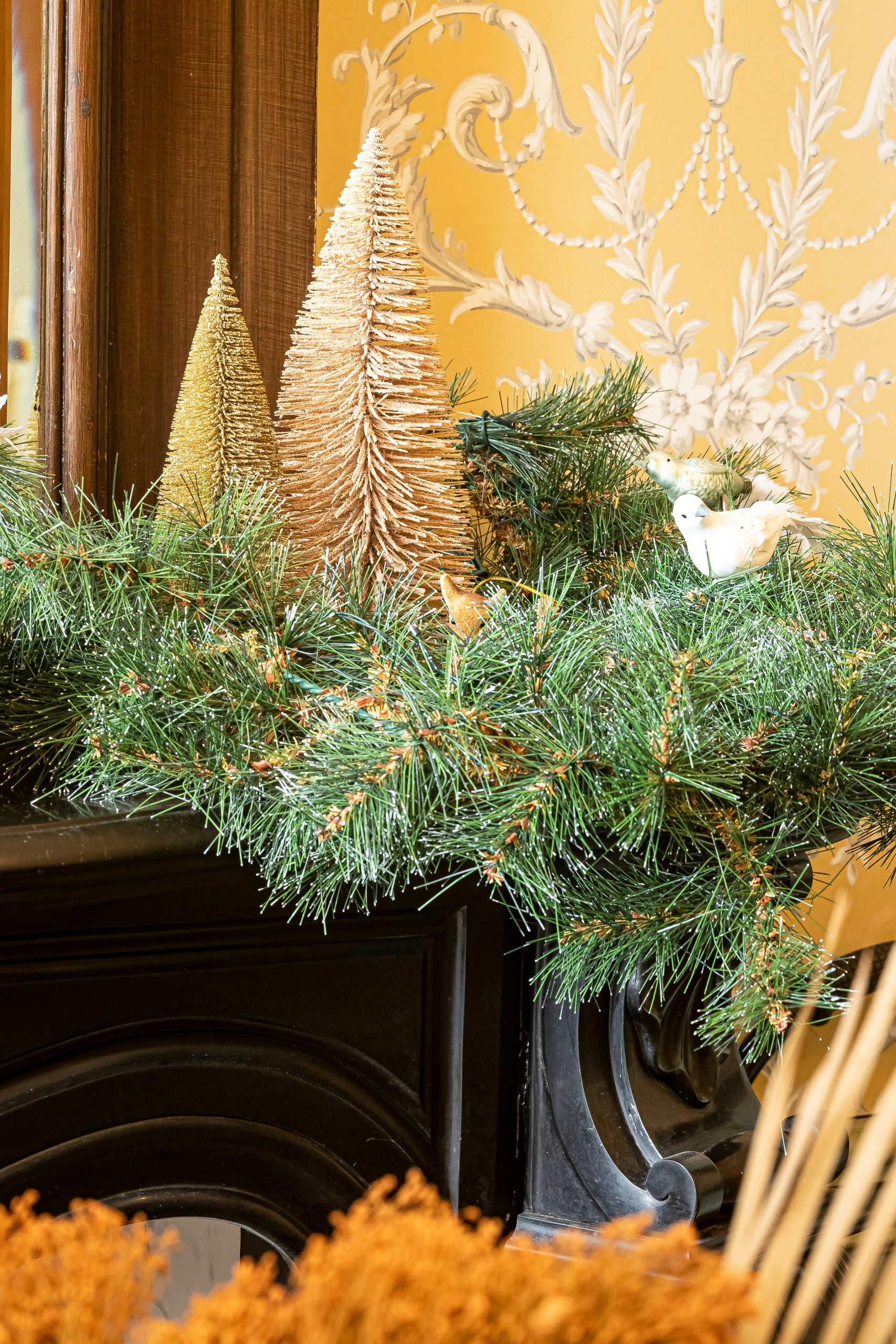 a fireplace mantel decorated with pine cones and evergreen branches