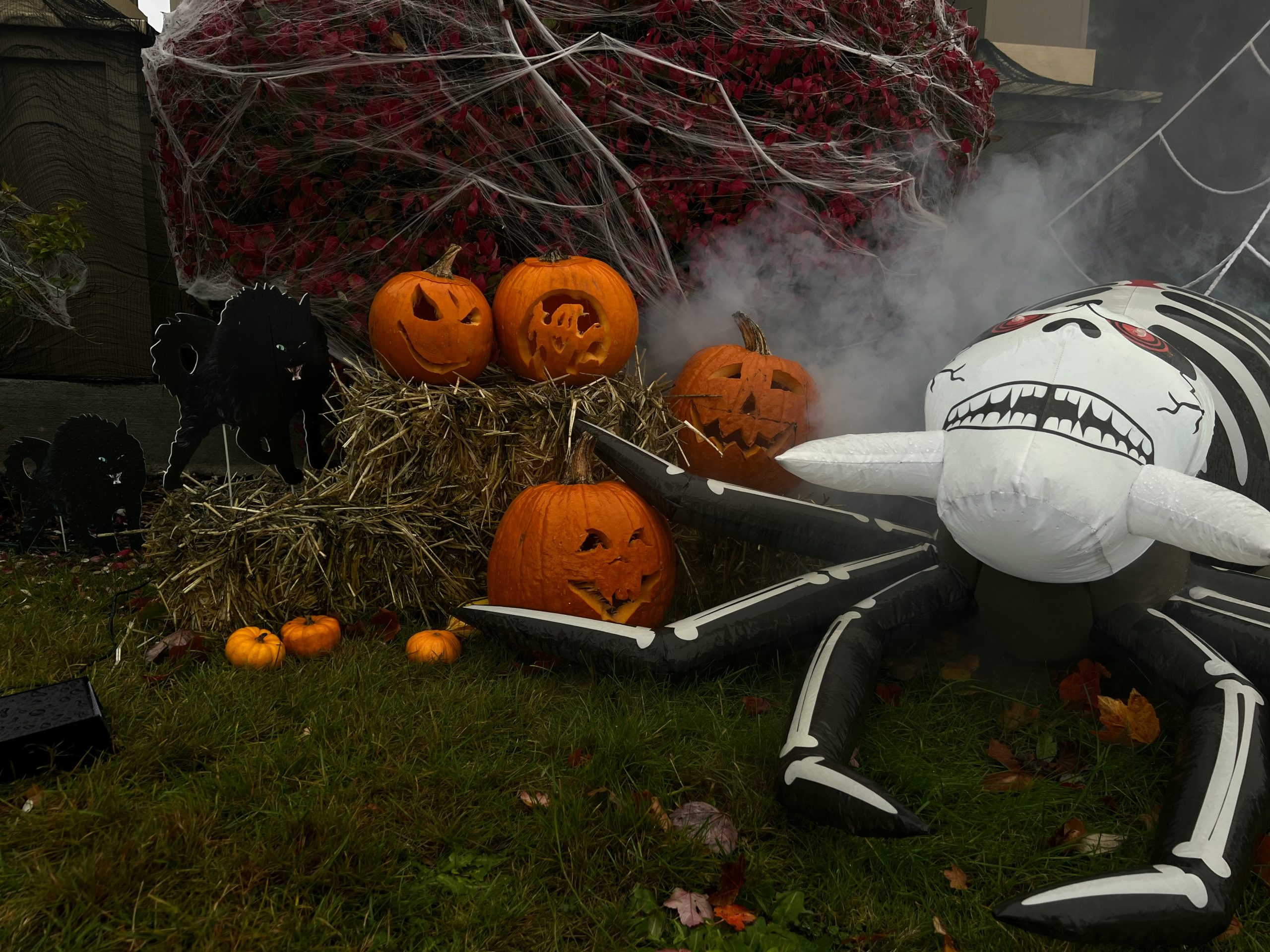 a large inflatable spider sitting next to a pile of pumpkins