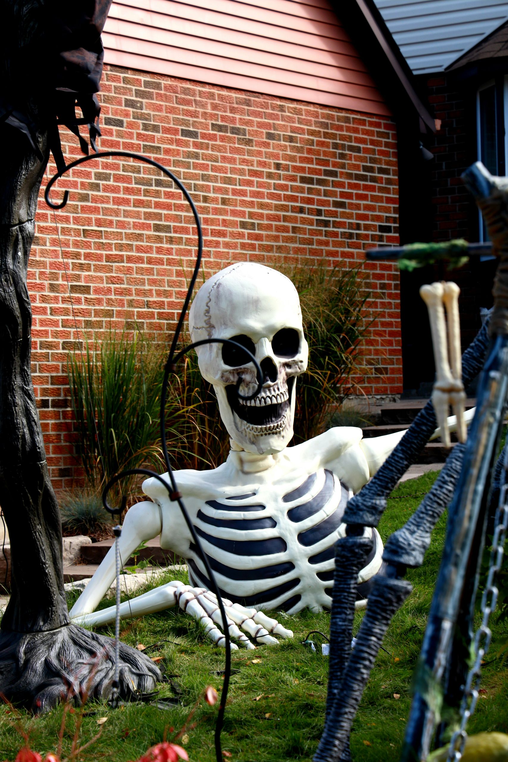 A large skeleton decoration sits on a lawn